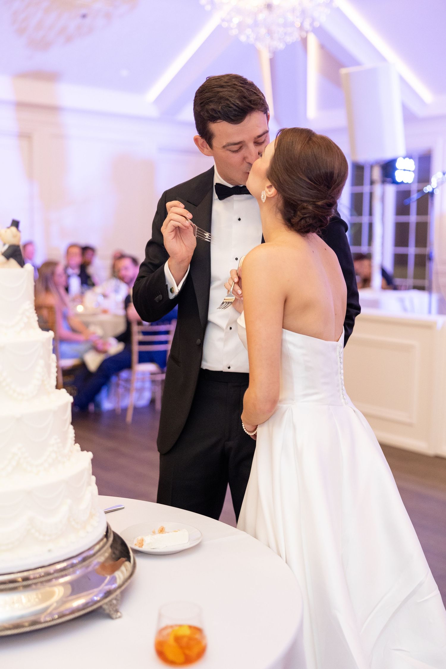 Groom feeding bride a bite of wedding cake during romantic reception celebration.