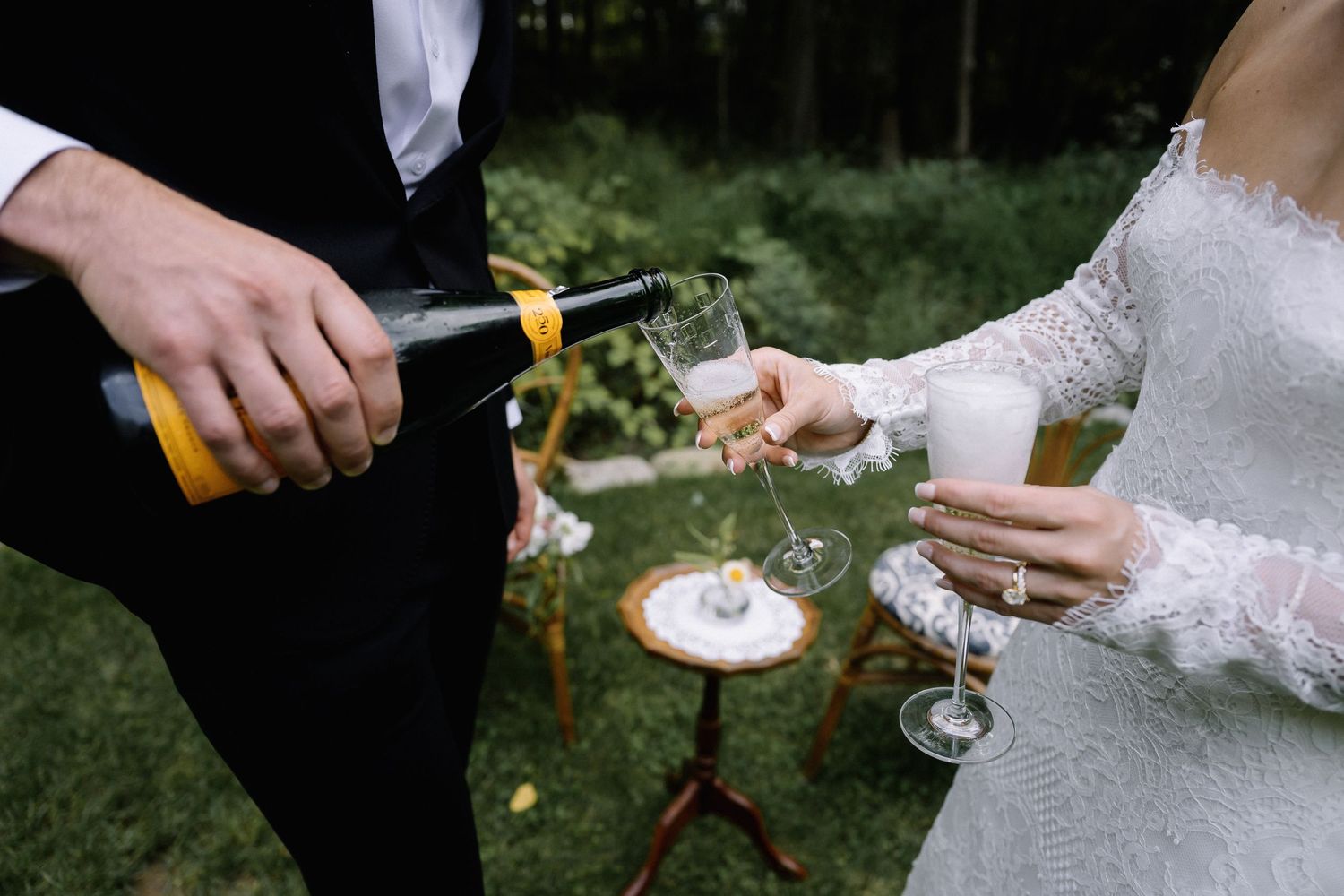 Wedding guests holding champagne glasses clink together in a celebratory outdoor garden toast.