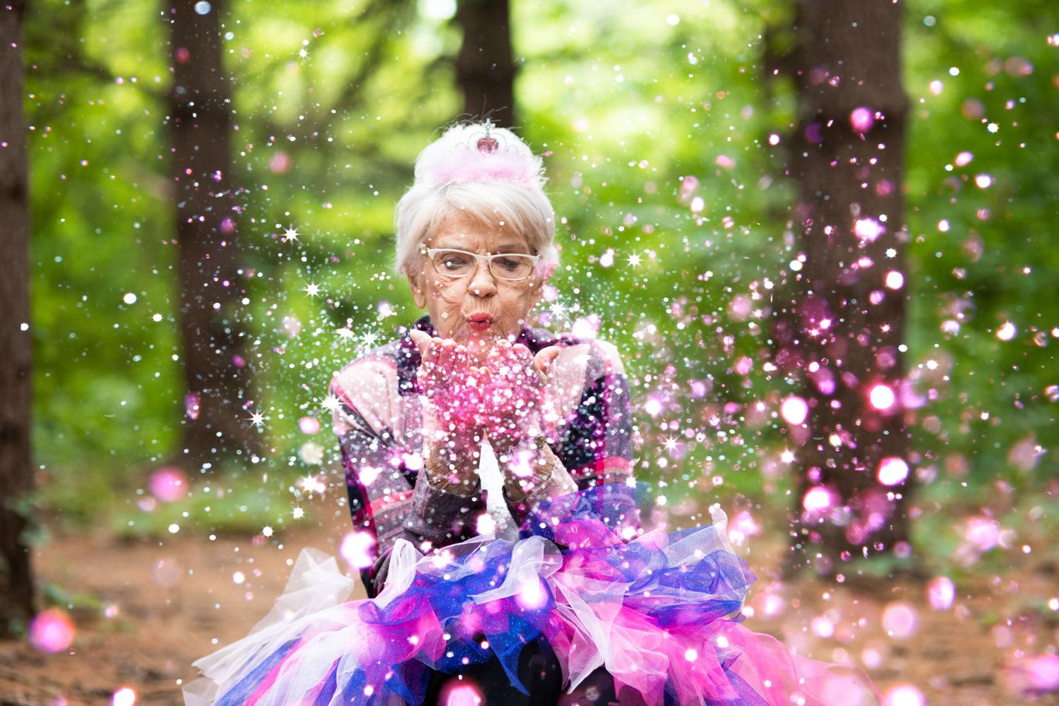 Magical forest scene with pink and purple confetti floating around a tulle dress in dreamy sunlit woodland.