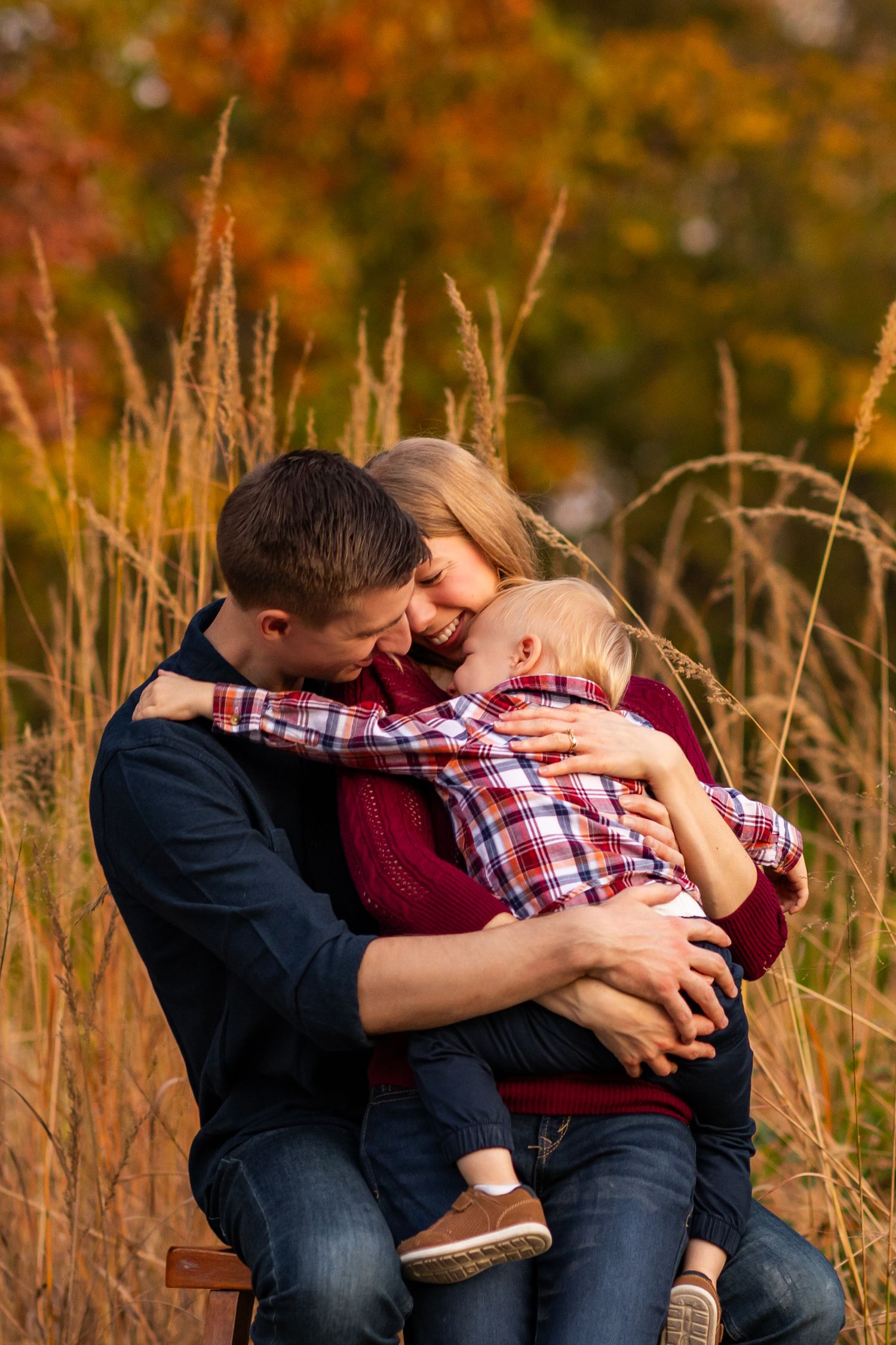 A tender moment shared in tall autumn grass with golden sunlight illuminating the background.