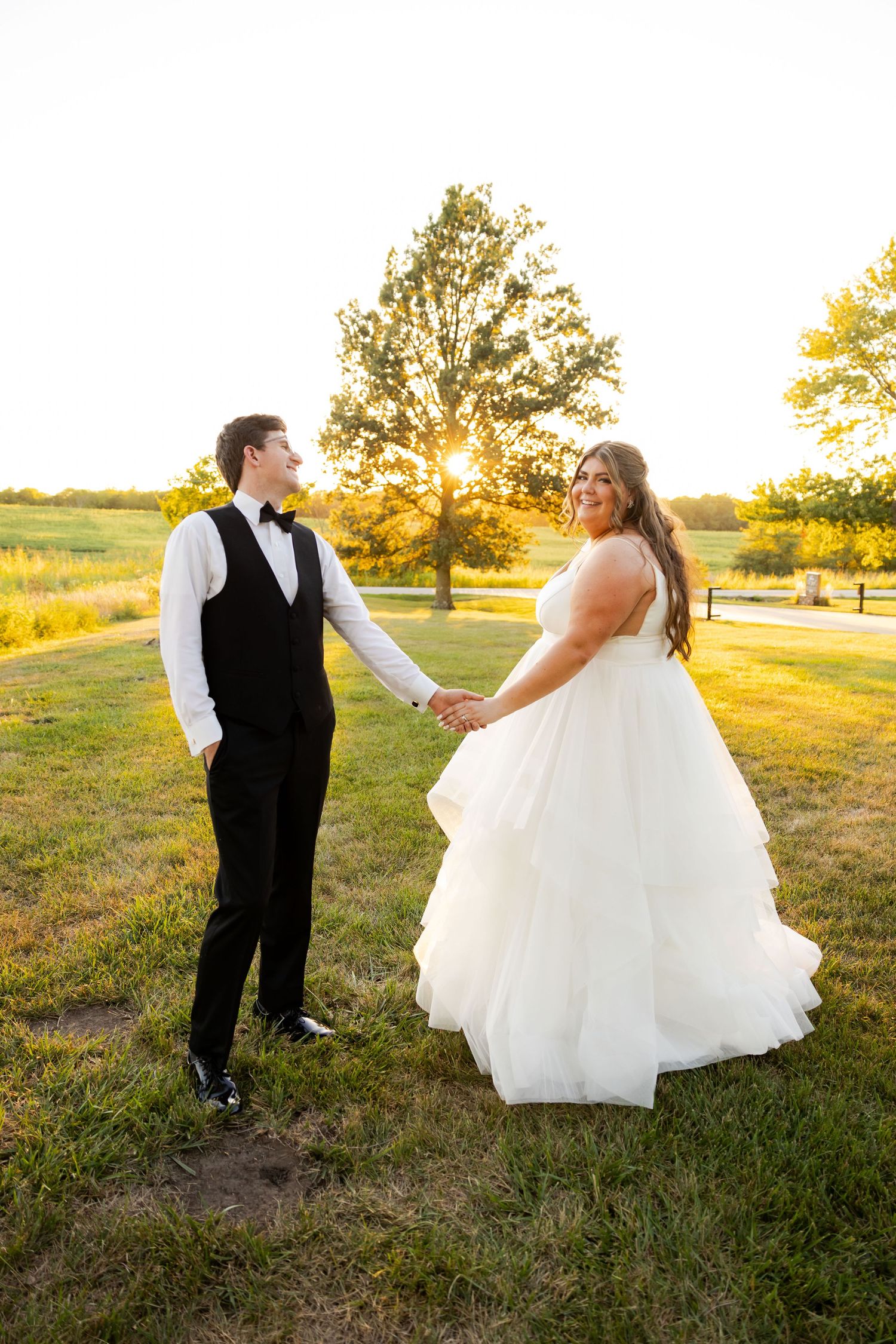 A couple holding hands during their sunset wedding photos on a beautiful golden autumn evening outdoors.