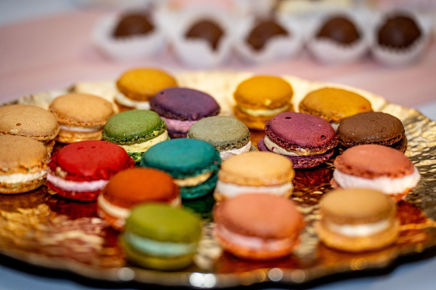 A colorful assortment of French macarons in various flavors displayed on a gold decorative plate.