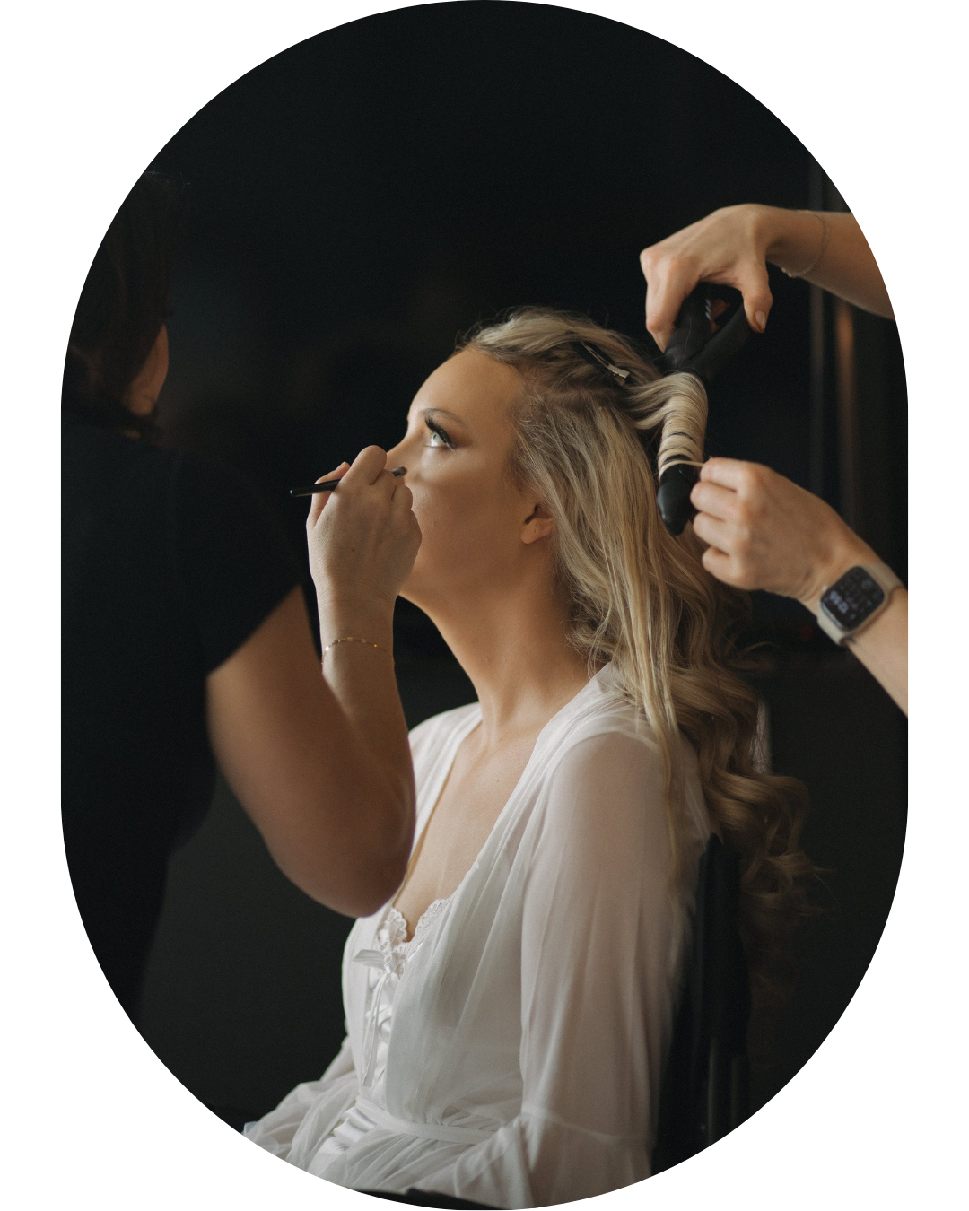 Getting ready scene with hair and makeup preparation in moody lighting.