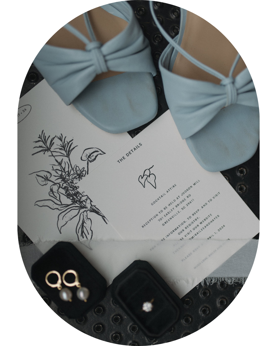 Wedding invitation with floral sketch design next to pale blue bow accessories and rings.