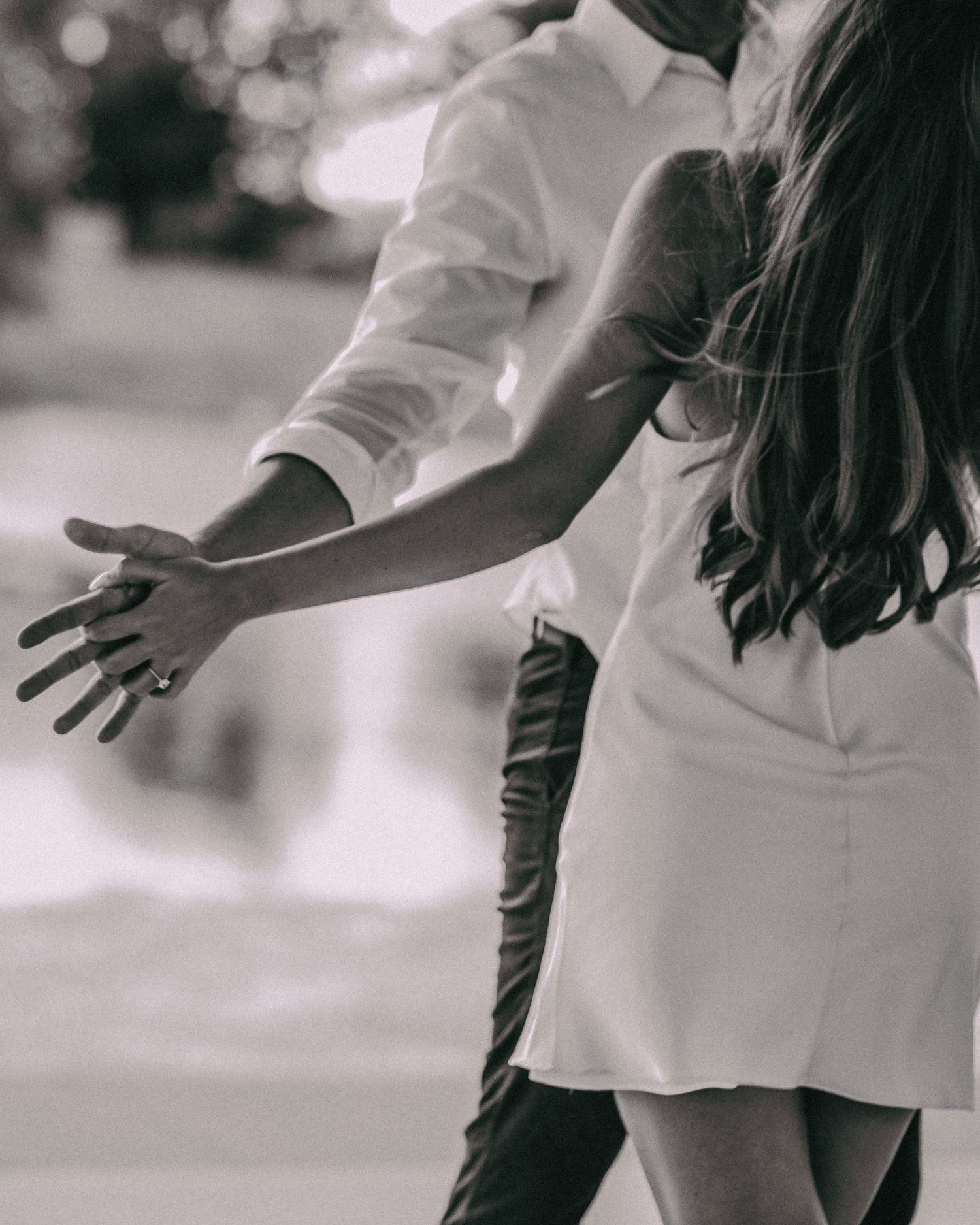 Black and white image of two people holding hands in elegant white clothing editorial wedding photography college station Texas