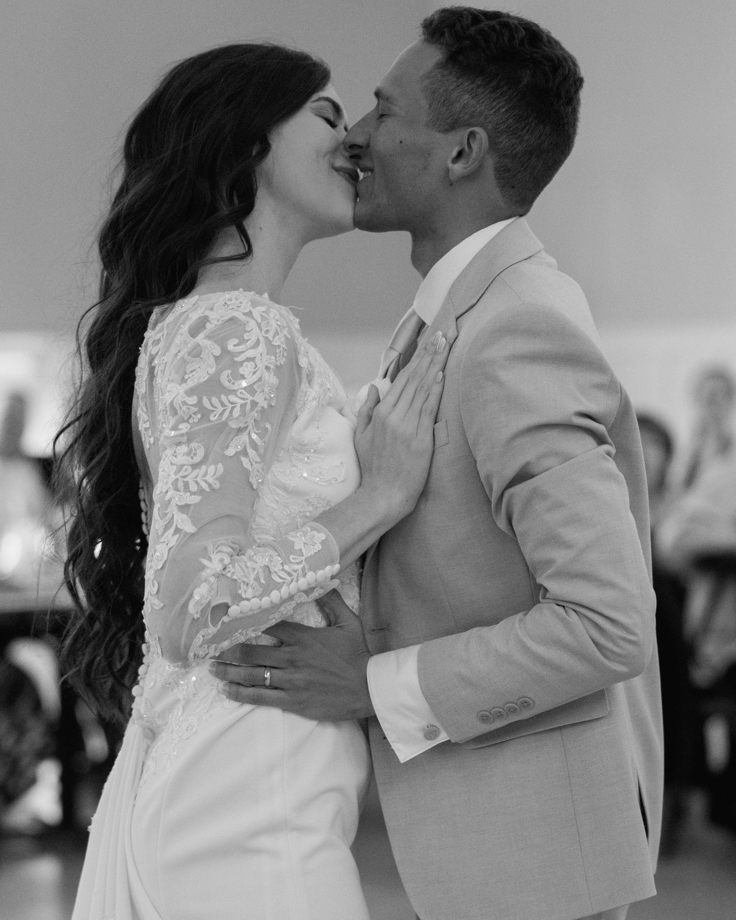 Black and white photo of bride and groom sharing first dance kiss at wedding.