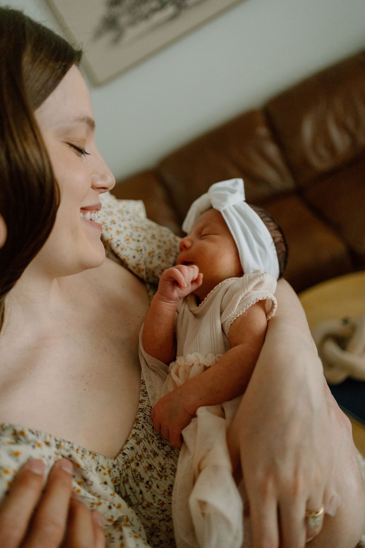 A tender moment between parent and baby against a brown leather couch backdrop.