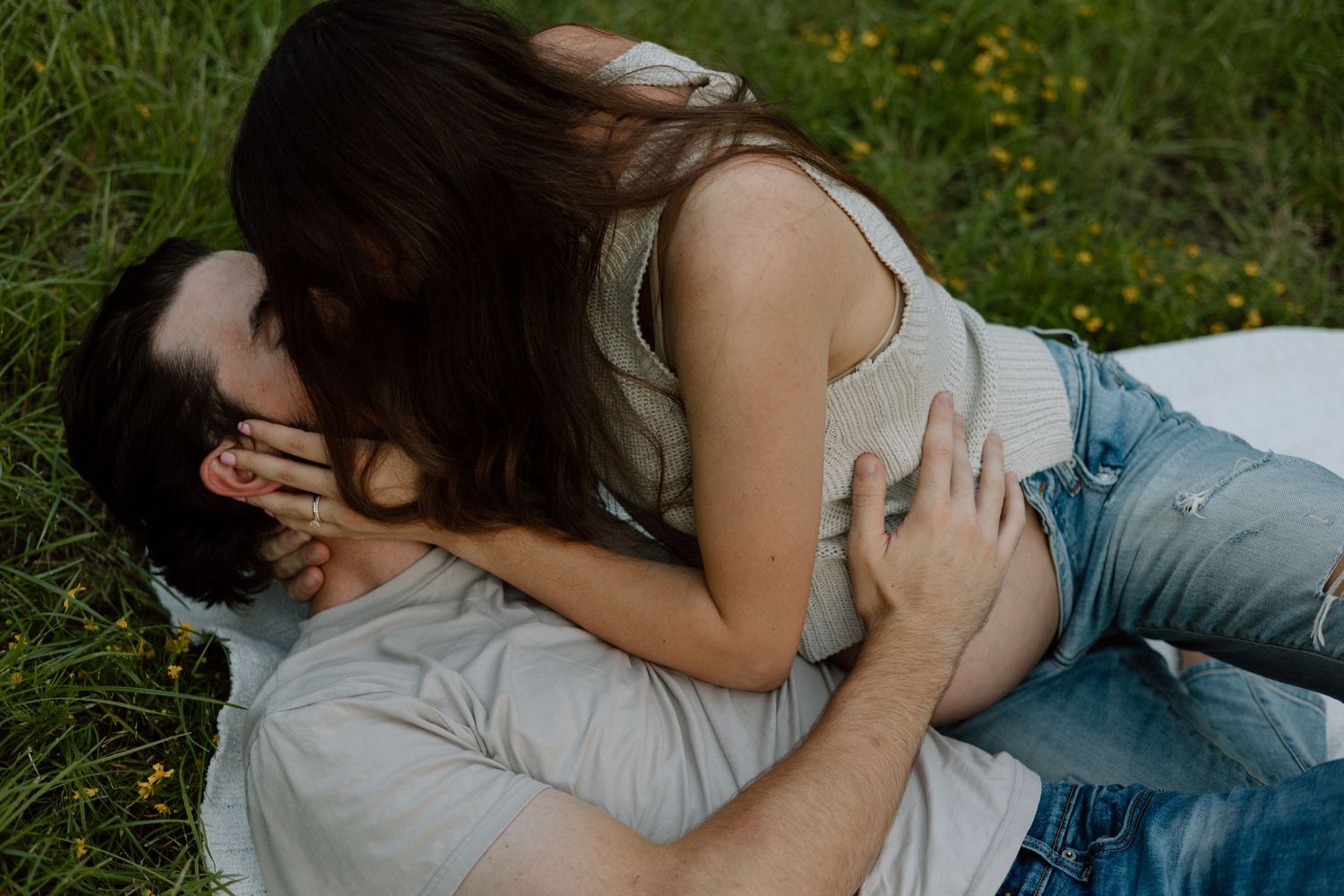 Intimate couple's maternity photo taken while lying in grassy field.