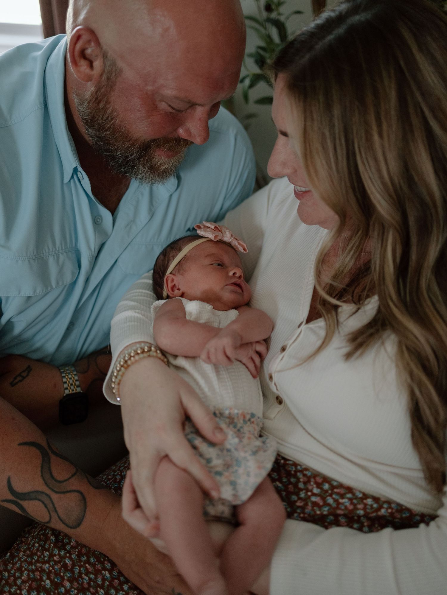 A couple gazes lovingly at their newborn baby during an intimate family photo session.