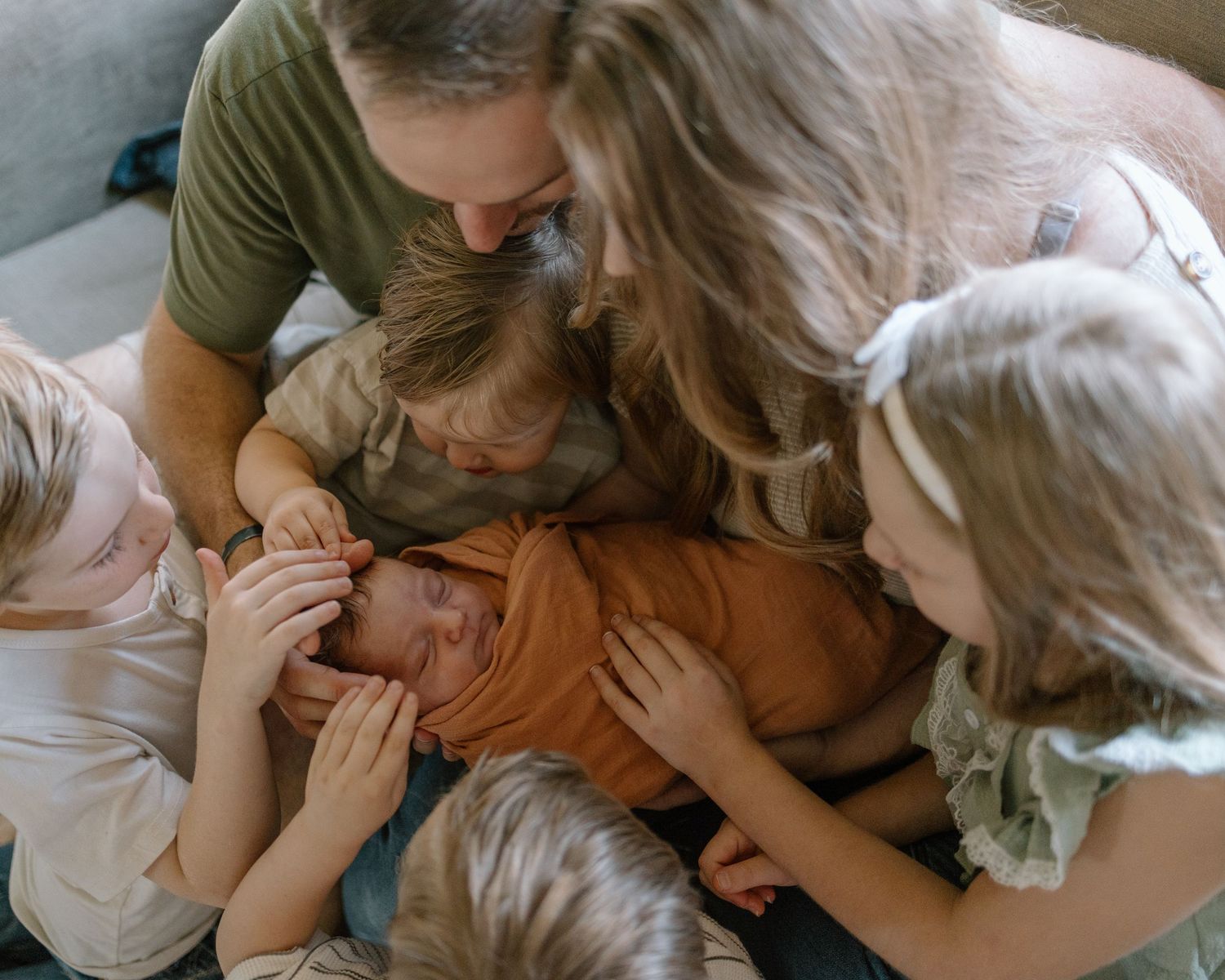 A family shares a playful moment while laying together on a light colored surface.