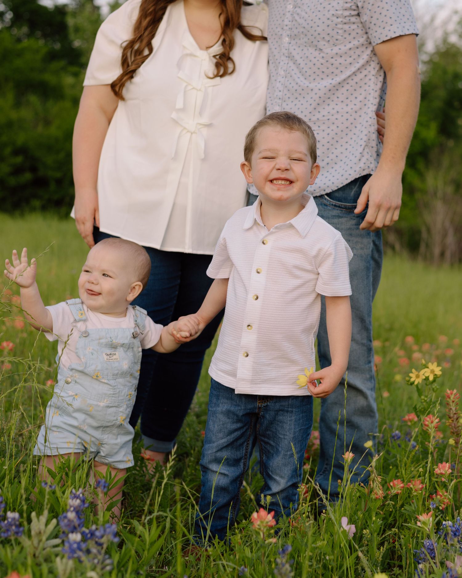 A family stands together in a wildflower meadow with vibrant blooms on a sunny spring afternoon.