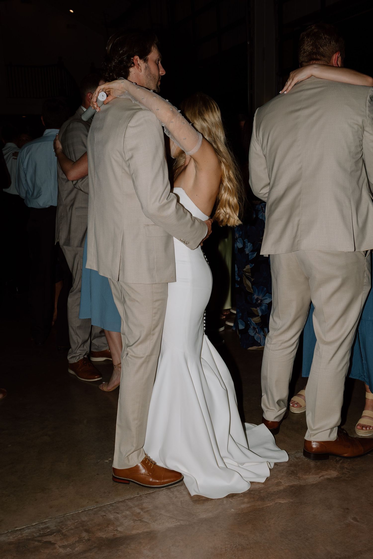 Couple dancing together at wedding reception with guests in formal attire.