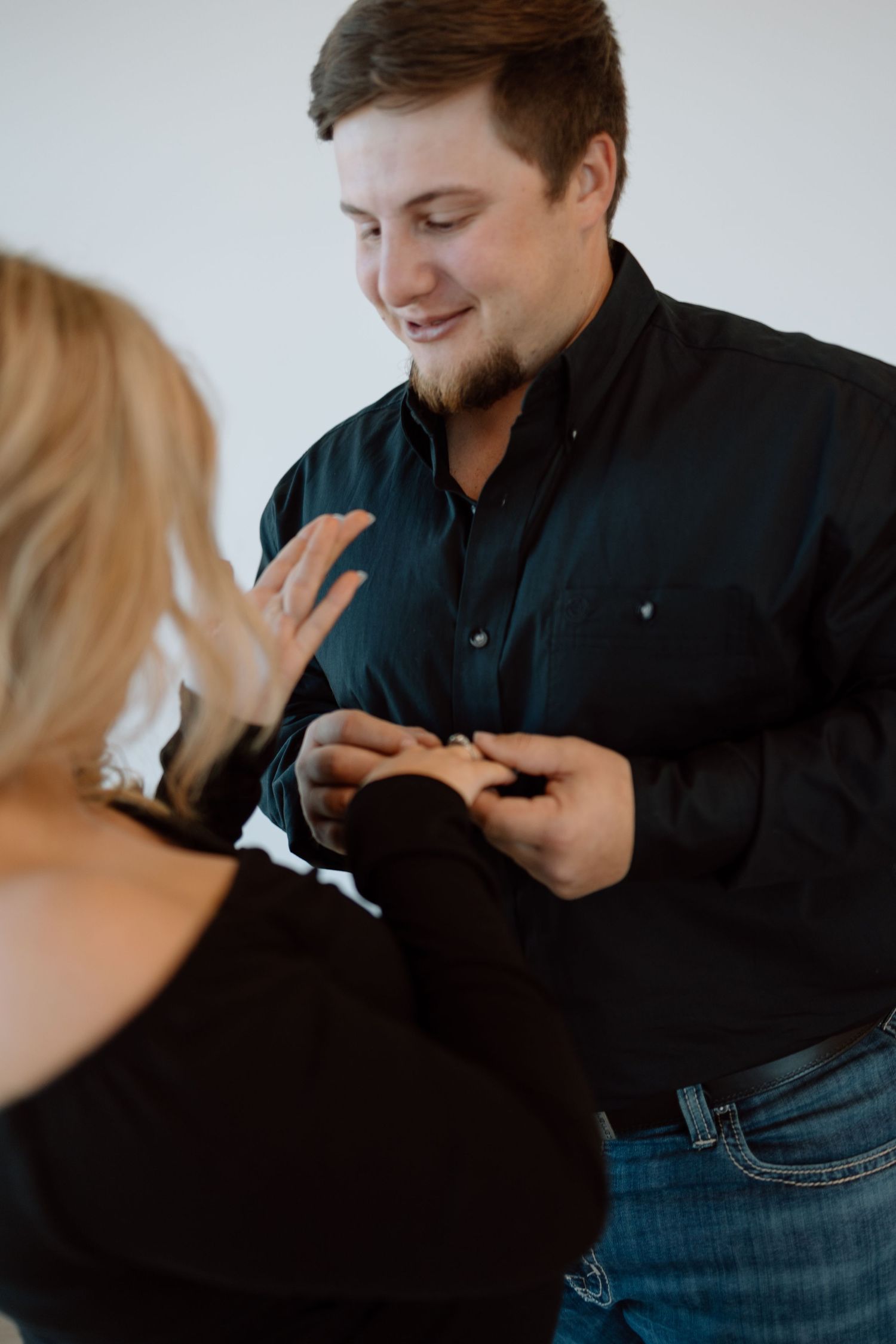 A couple shares an intimate moment as they exchange rings during what appears to be an engagement or wedding proposal.