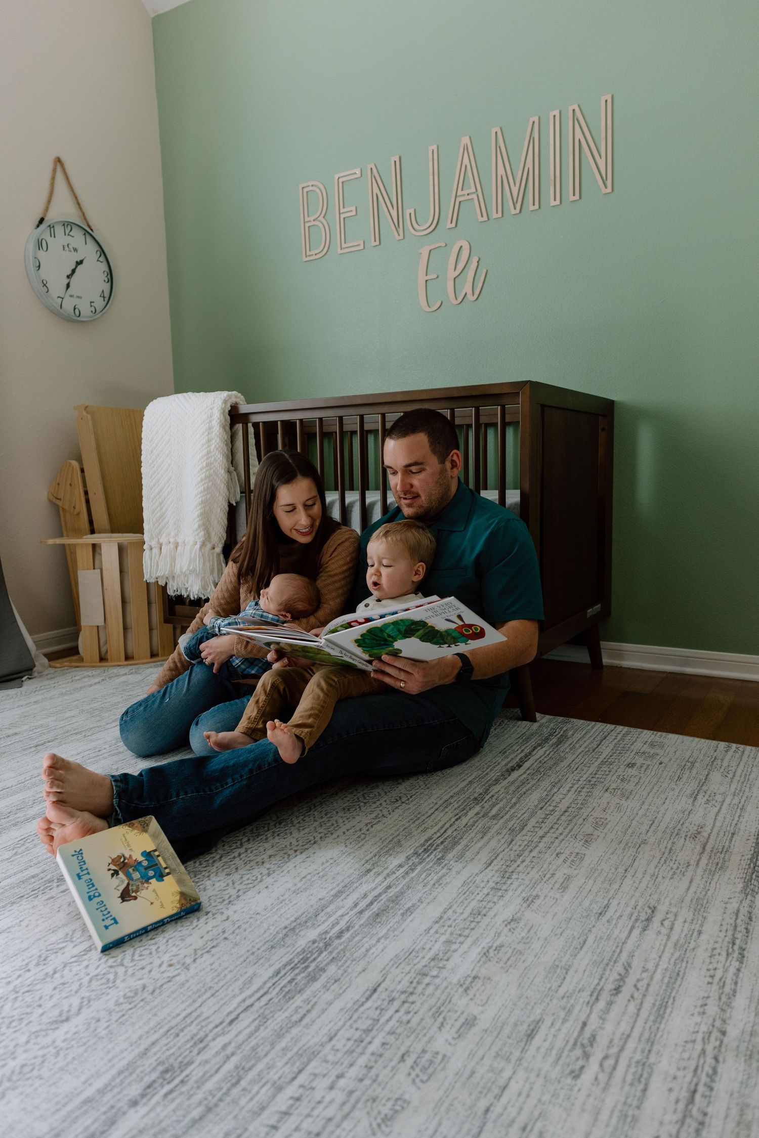 Family reading storybooks together in a cozy nursery with mint green walls and Benjamin lettering decor.