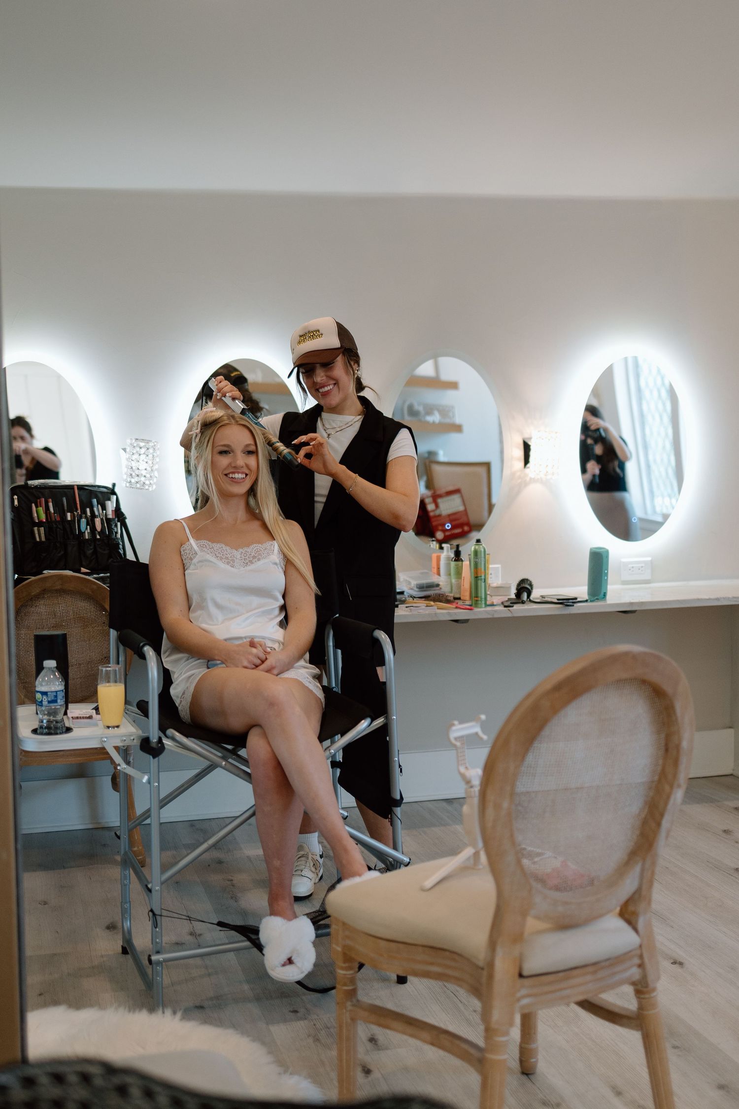 Getting ready scene in bridal salon with illuminated mirrors.