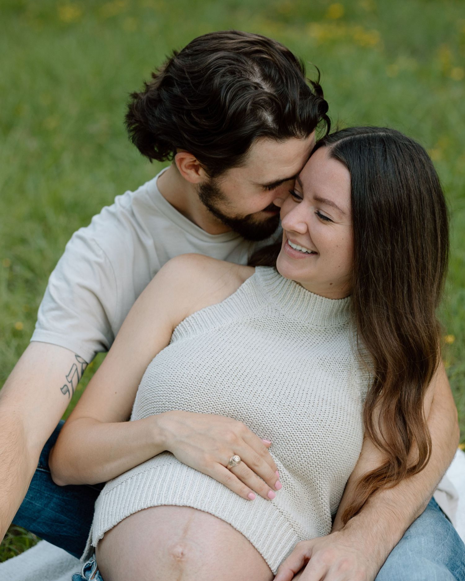 Intimate maternity portrait with couple sharing tender moment outdoors.