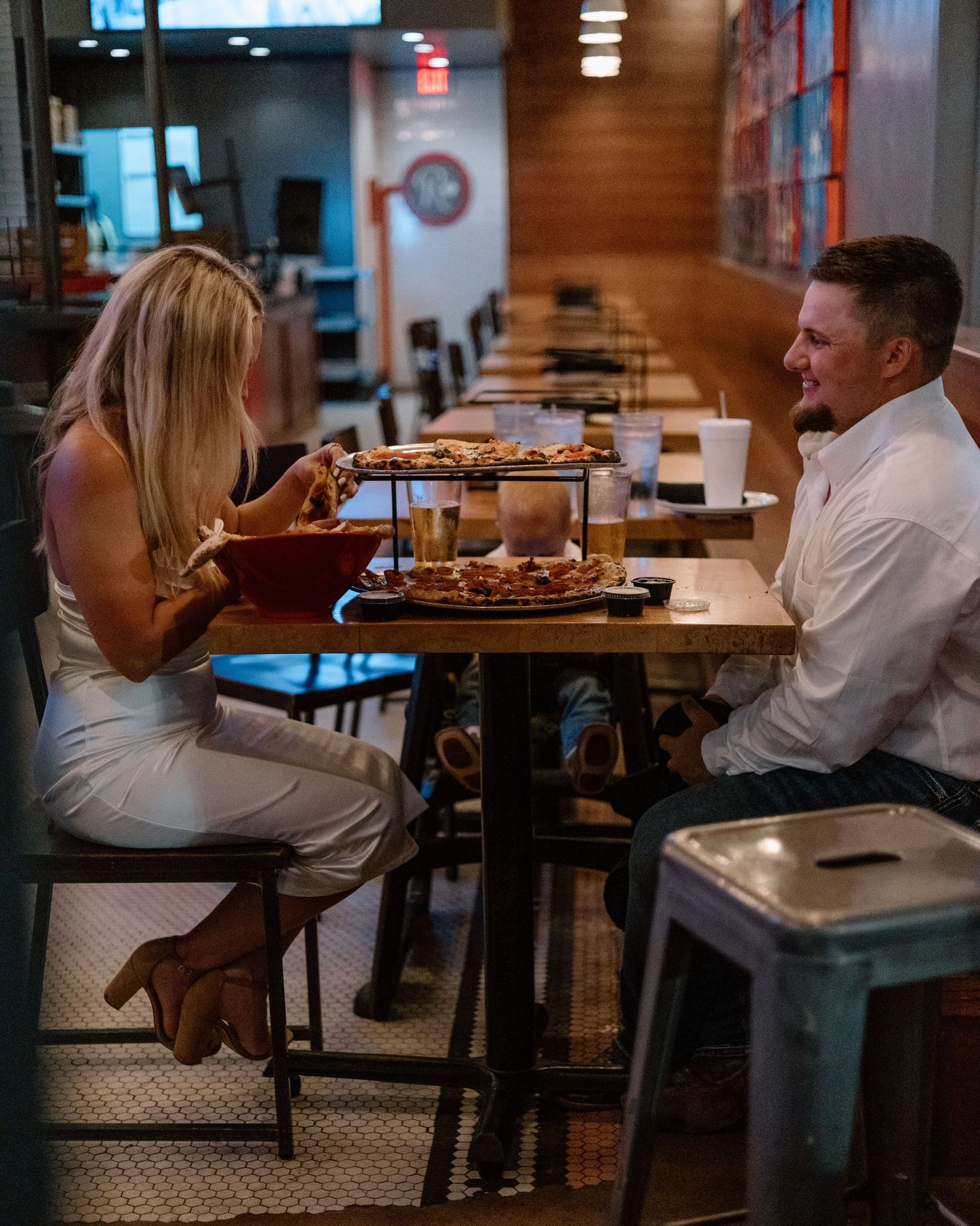 Couple enjoying pizza together on a date at a casual modern restaurant with warm lighting.