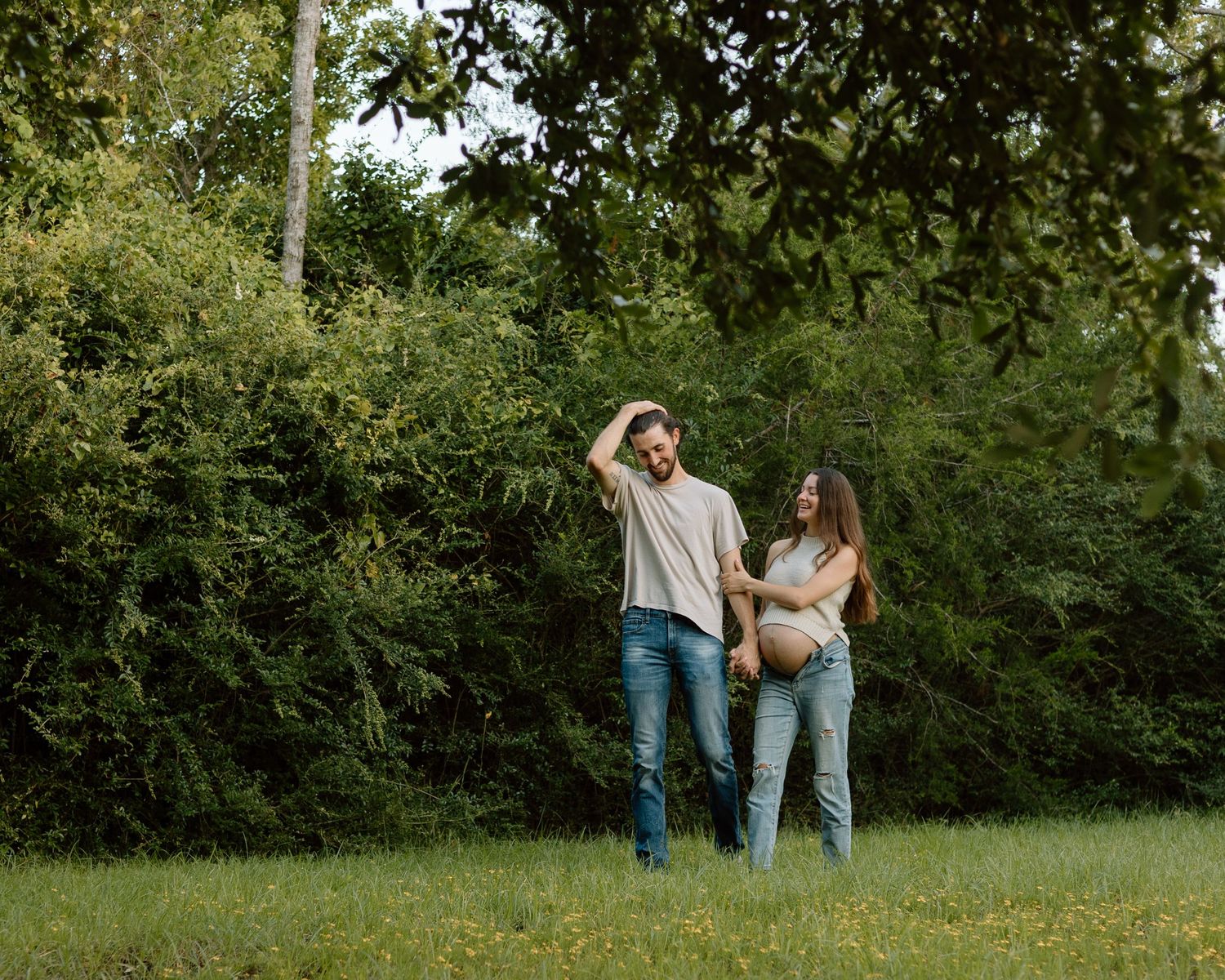 A couple shares a tender moment while standing together in a lush green garden setting.