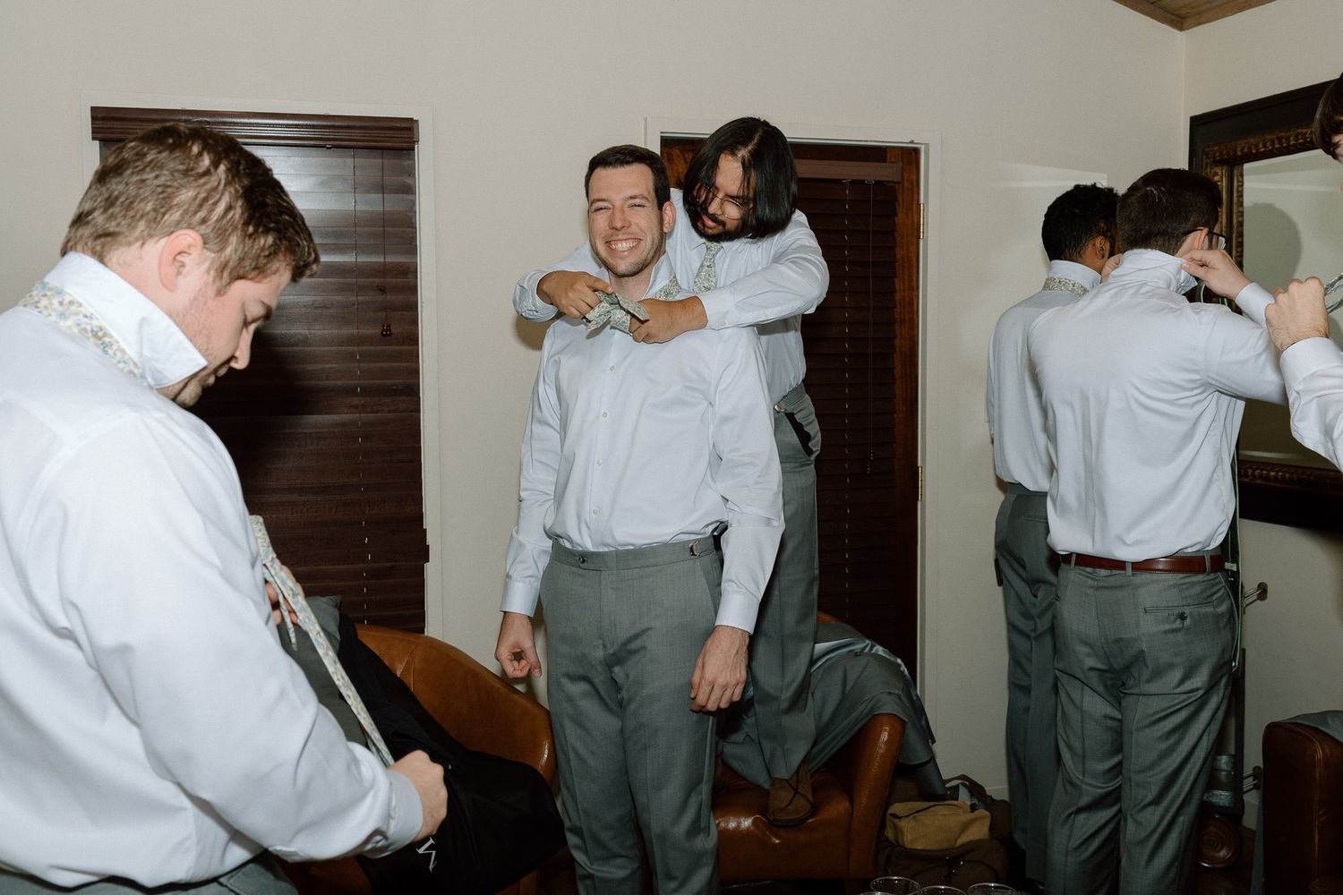 Wedding party members getting ready in a room with wood doors.
