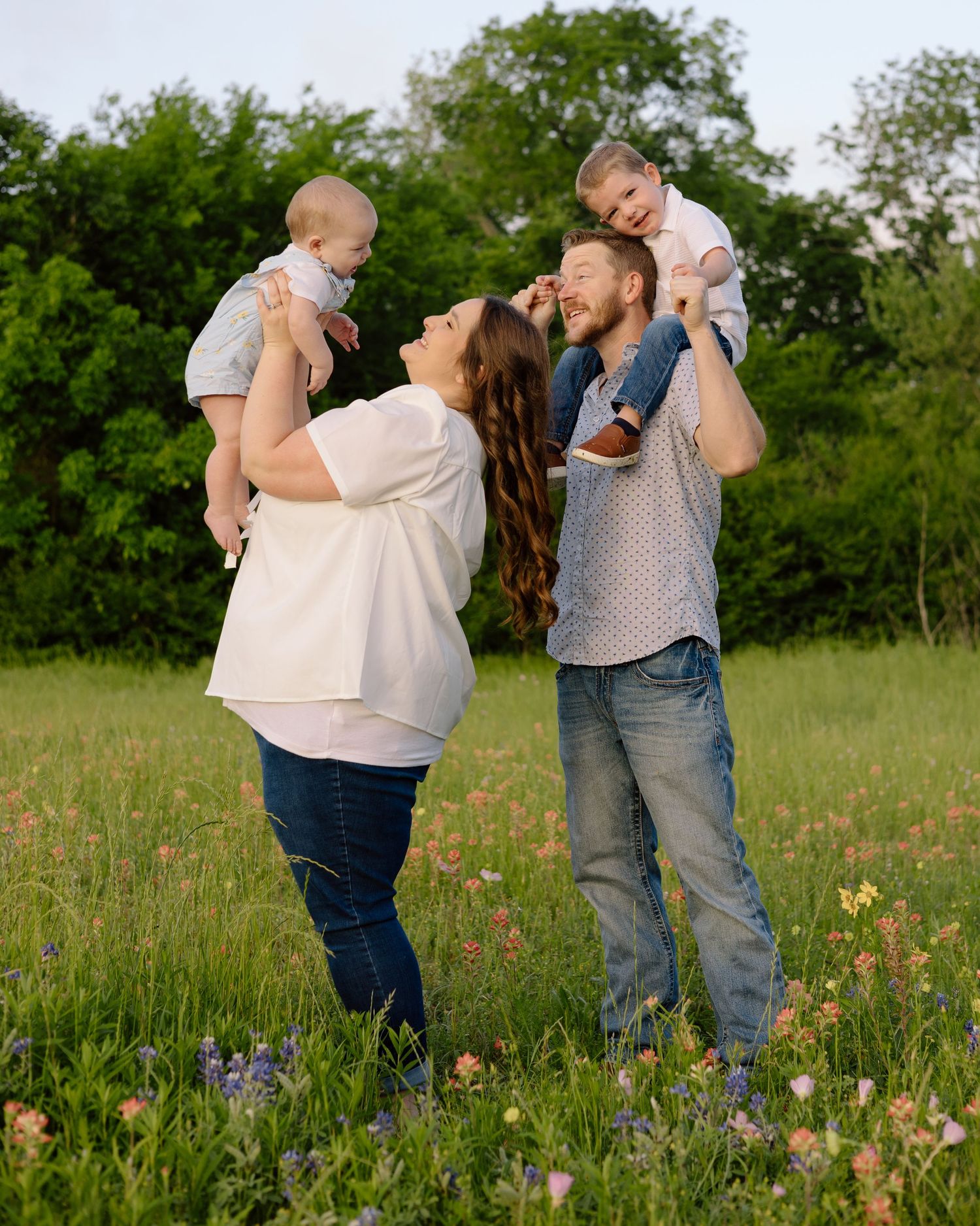 Family enjoys a playful moment together in a wildflower meadow during springtime.