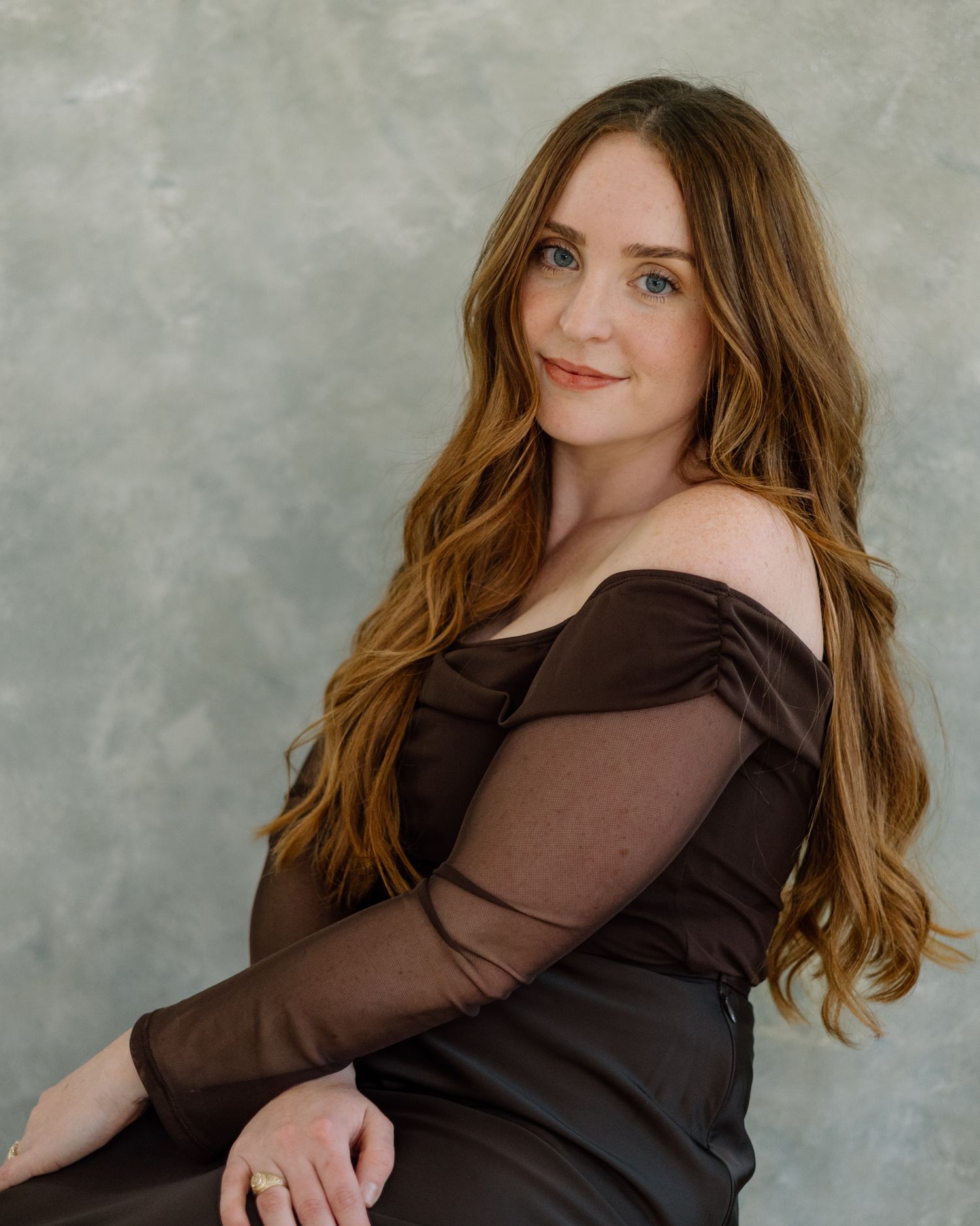 A series of portrait photos showing someone with long wavy brown hair wearing a dark brown long-sleeved top against a gray backdrop.