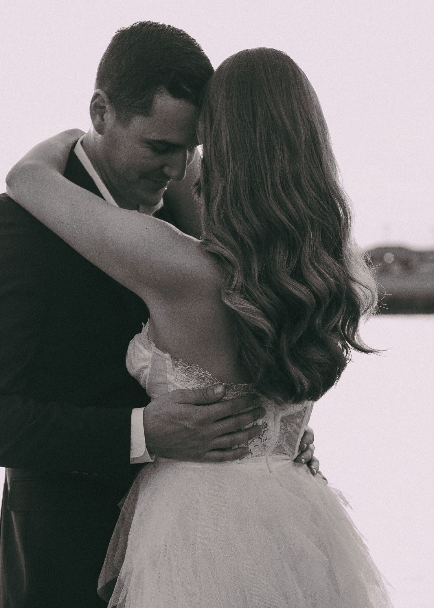 A black and white romantic portrait of a couple in an intimate embrace.