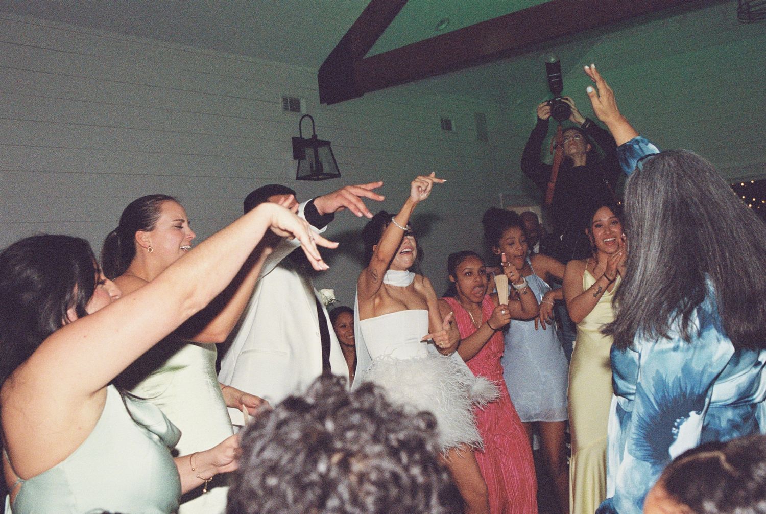 Celebratory crowd with raised arms dancing during a wedding reception party.
