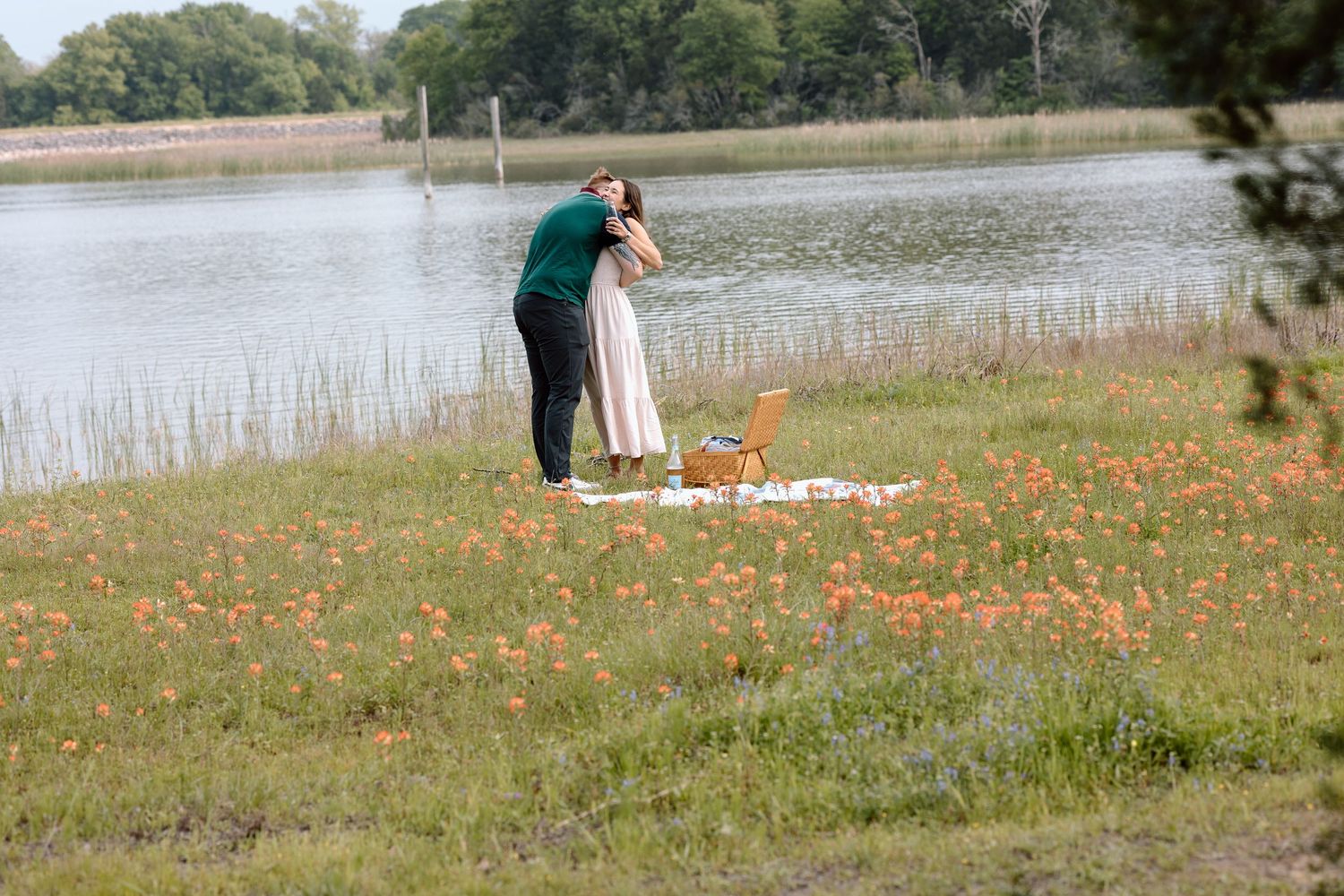 A couple having a romantic moment in a field of orange wildflowers near a lake on a sunny day documentary photography college station Texas.