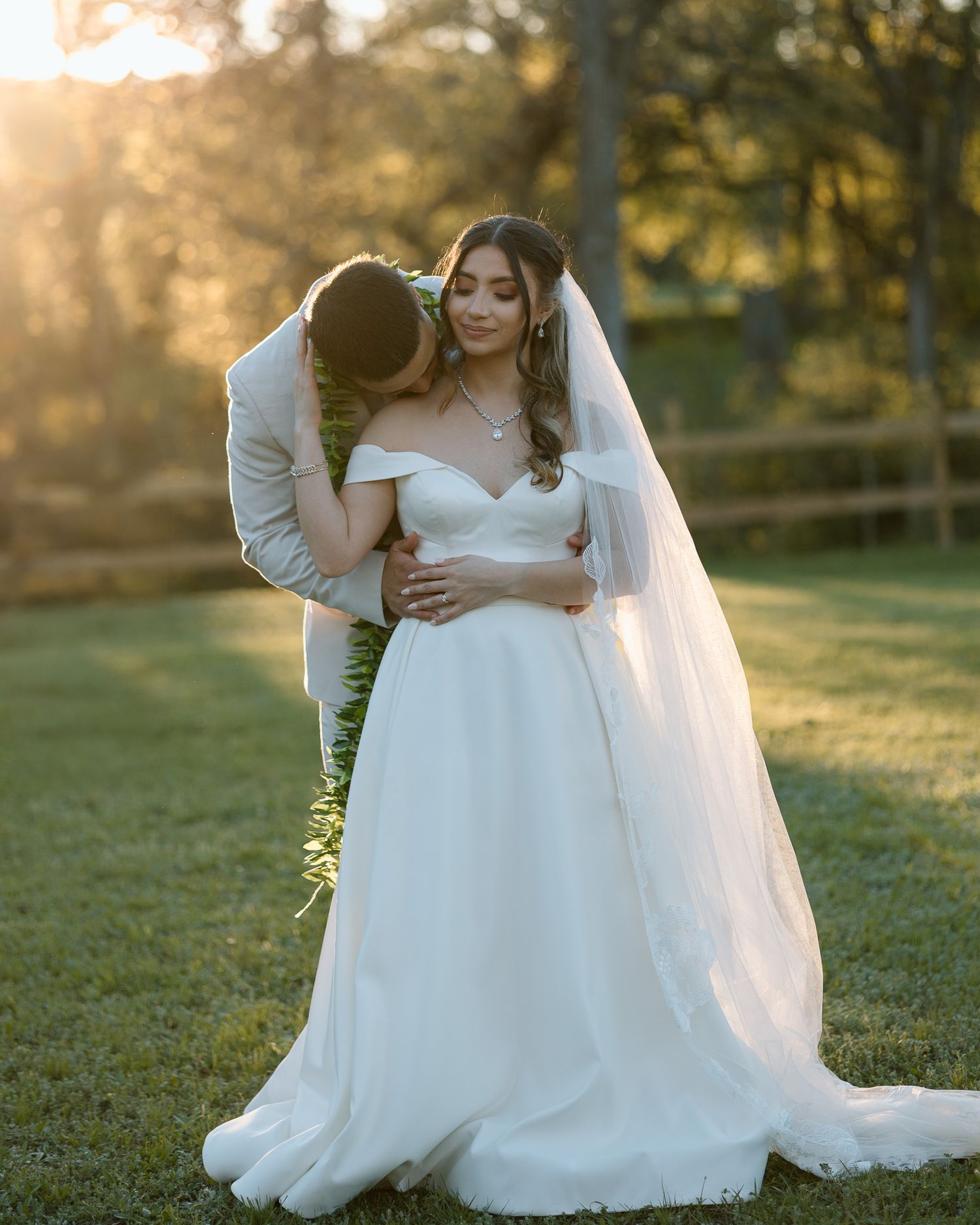 Romantic sunset portrait of newlyweds embracing in outdoor garden setting.