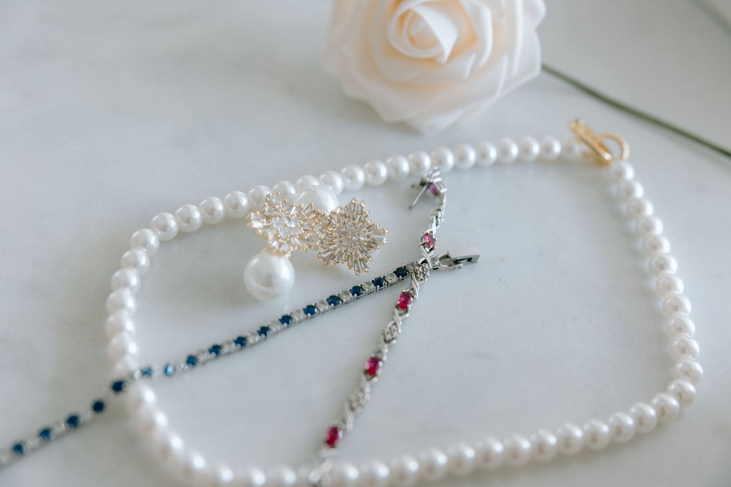 Pearl necklace and crystal earrings displayed as bridal accessories.