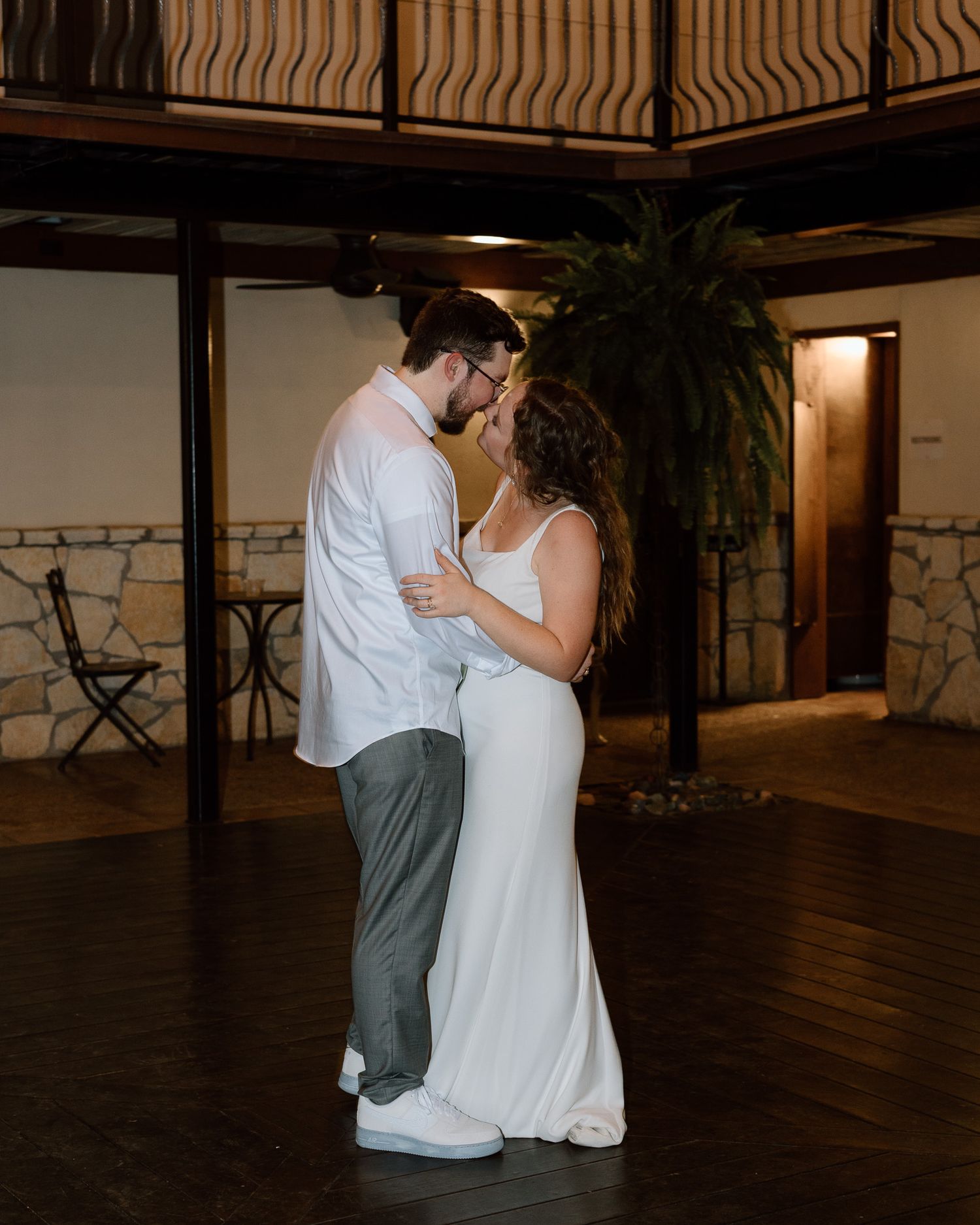 A romantic slow dance moment between newlyweds on a dimly lit terrace.
