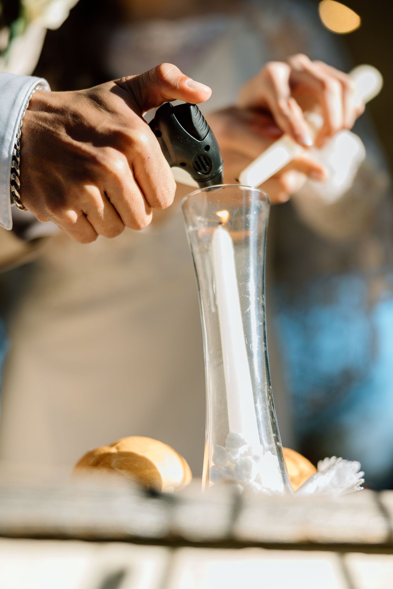 Close-up of hands pouring white sand into unity vase during wedding ceremony.
