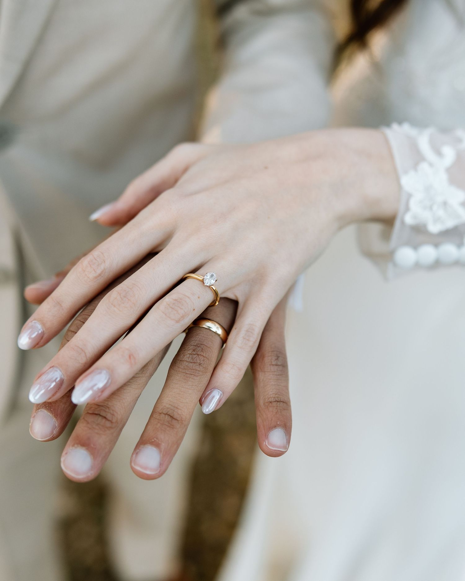 Close-up of newlyweds hands showing gold wedding band and diamond solitaire engagement ring after ceremony.