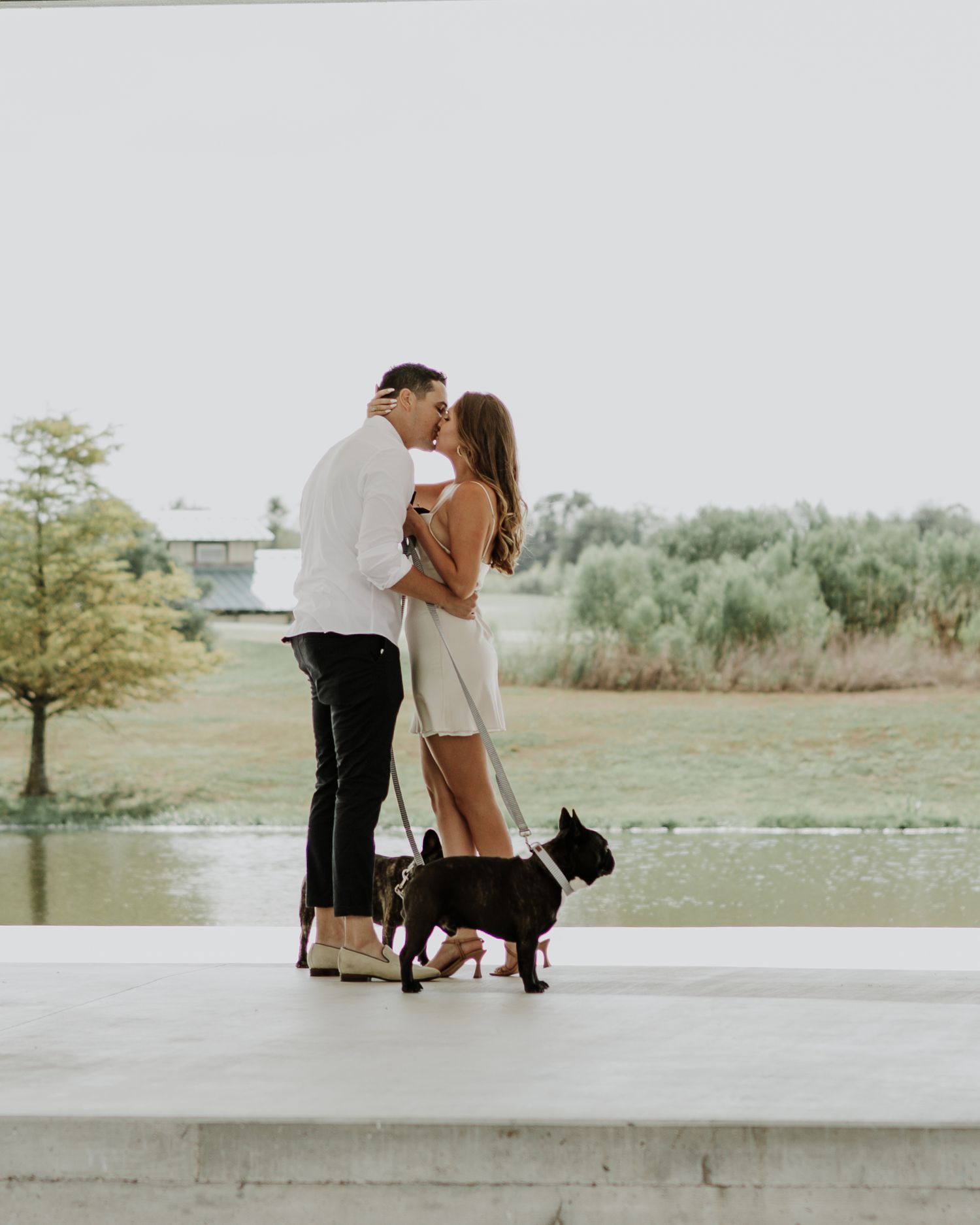 A romantic moment shared between a couple with their dog by the waterfront.