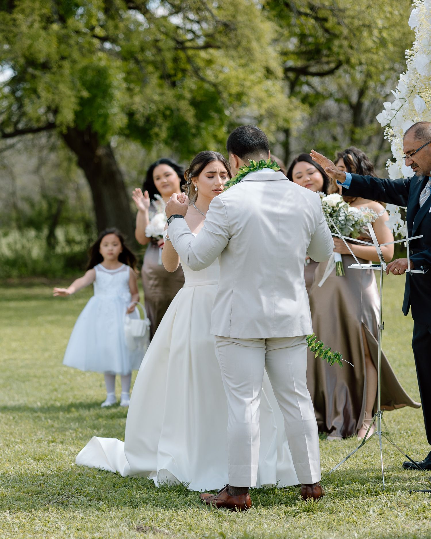 Wedding couple dances surrounded by guests at outdoor garden reception.