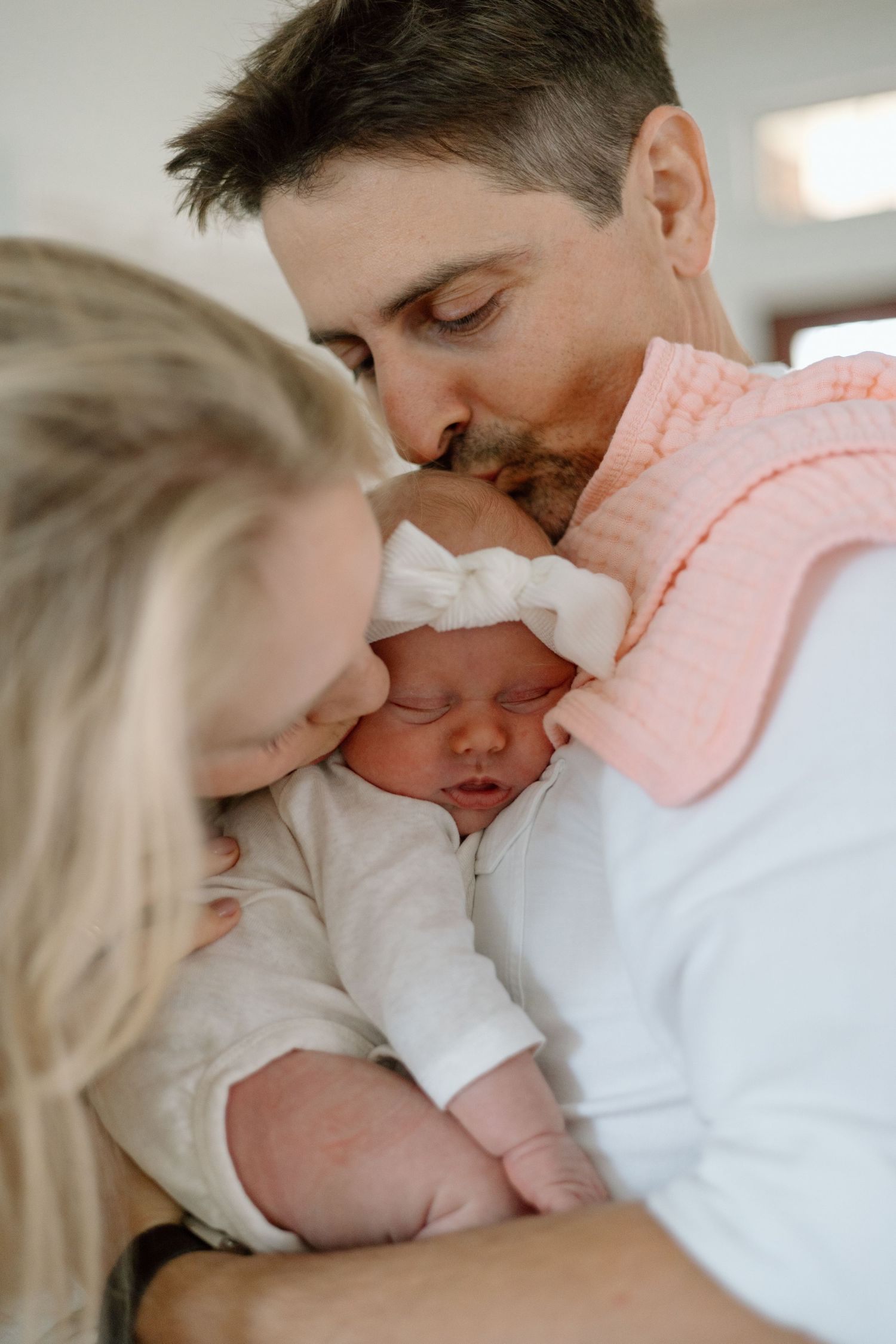 Parents sharing intimate moment with sleeping newborn between them.