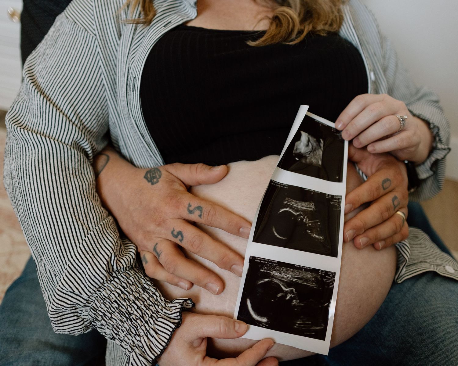 Close up of hands holding ultrasound strip against pregnant belly in intimate moment.