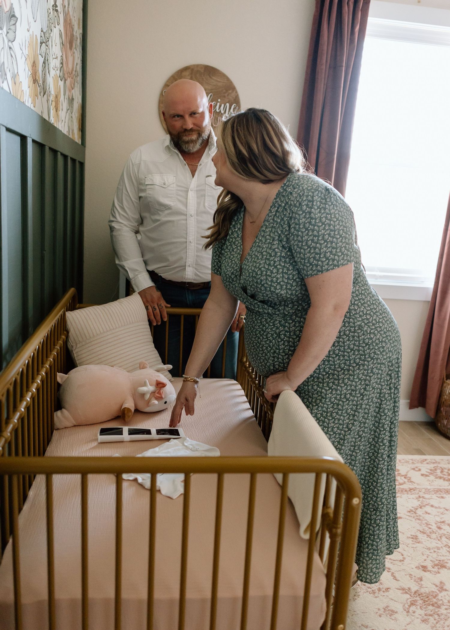 A couple looks at ultrasound photos displayed in a wooden baby crib.