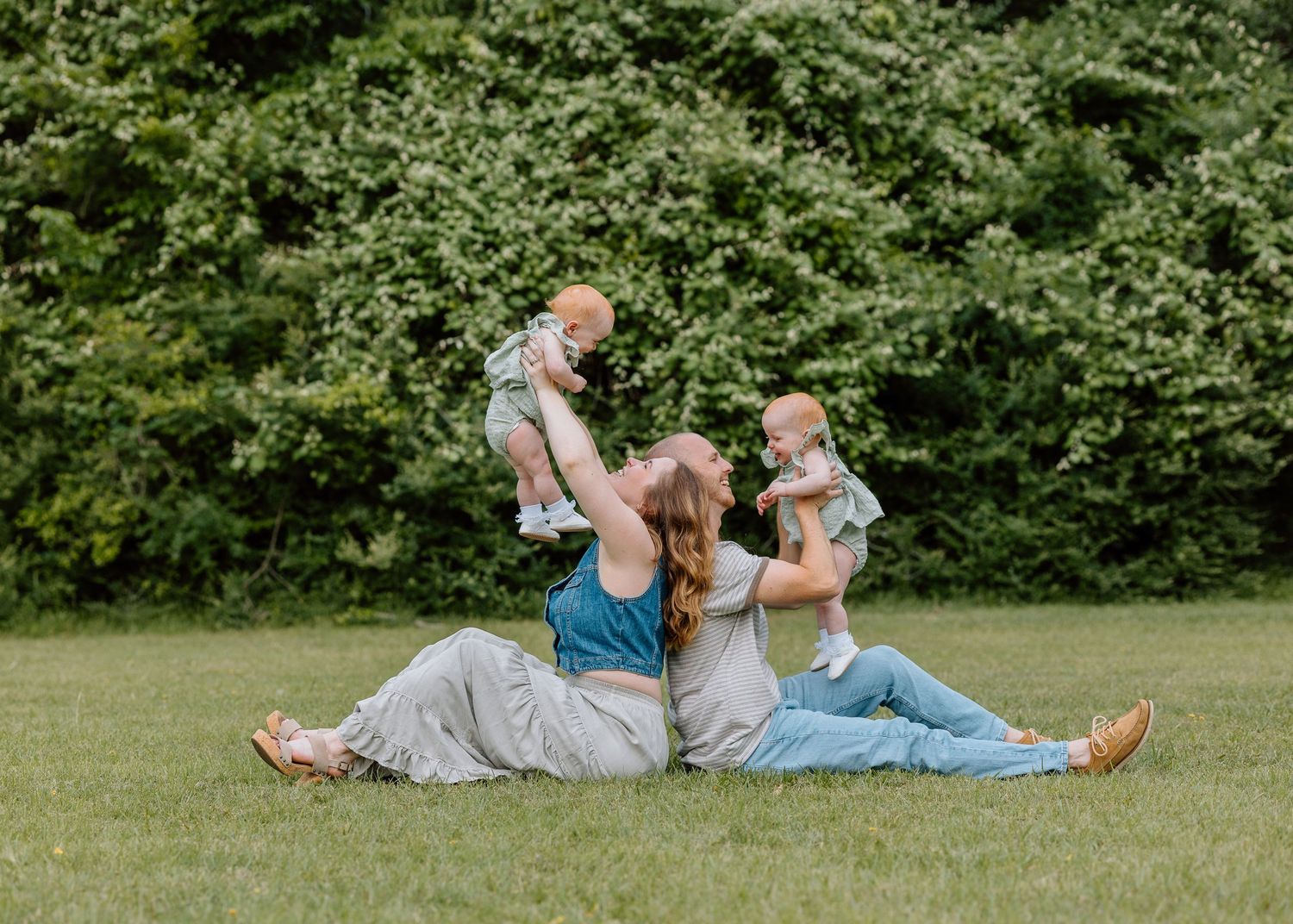 Happy family spending time together on green grass in a park on a sunny summer day.