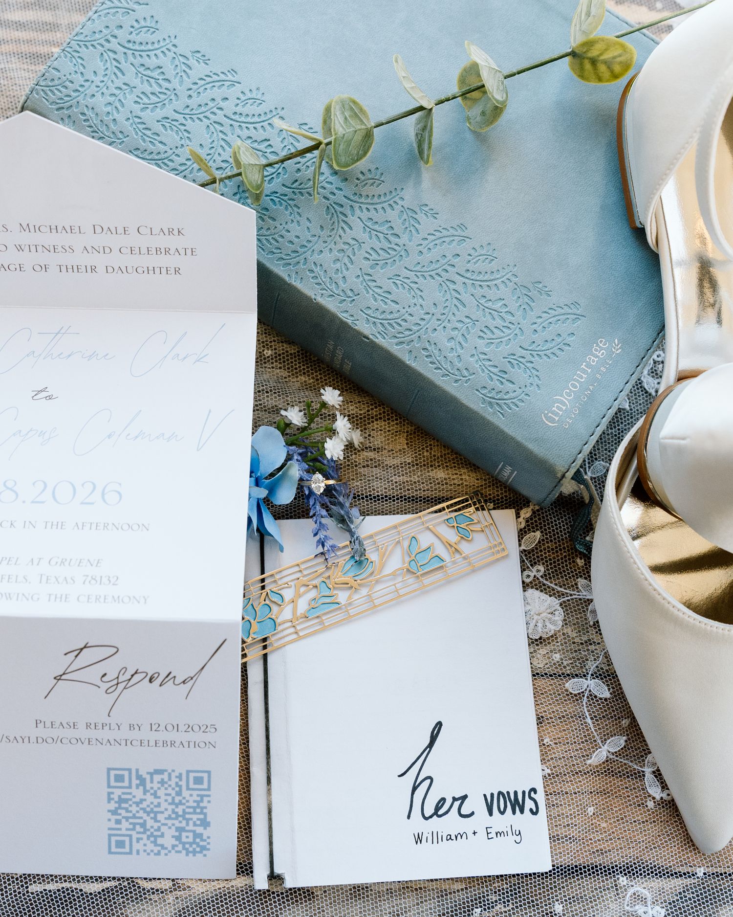 Elegant wedding stationery suite in dusty blue featuring vow booklets, floral invitations, and a QR code RSVP card on rustic wood.