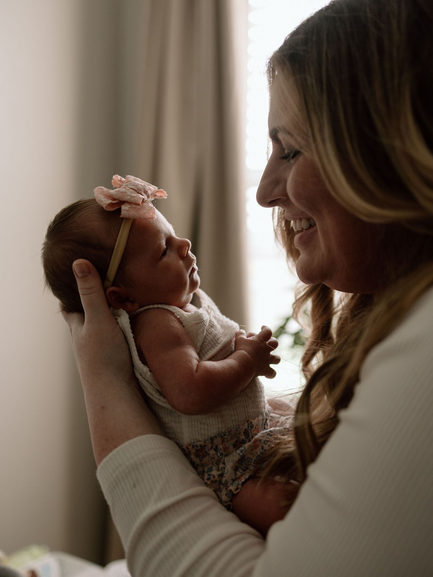 A tender moment between mother and newborn baby in soft natural light as they share a heartwarming exchange.