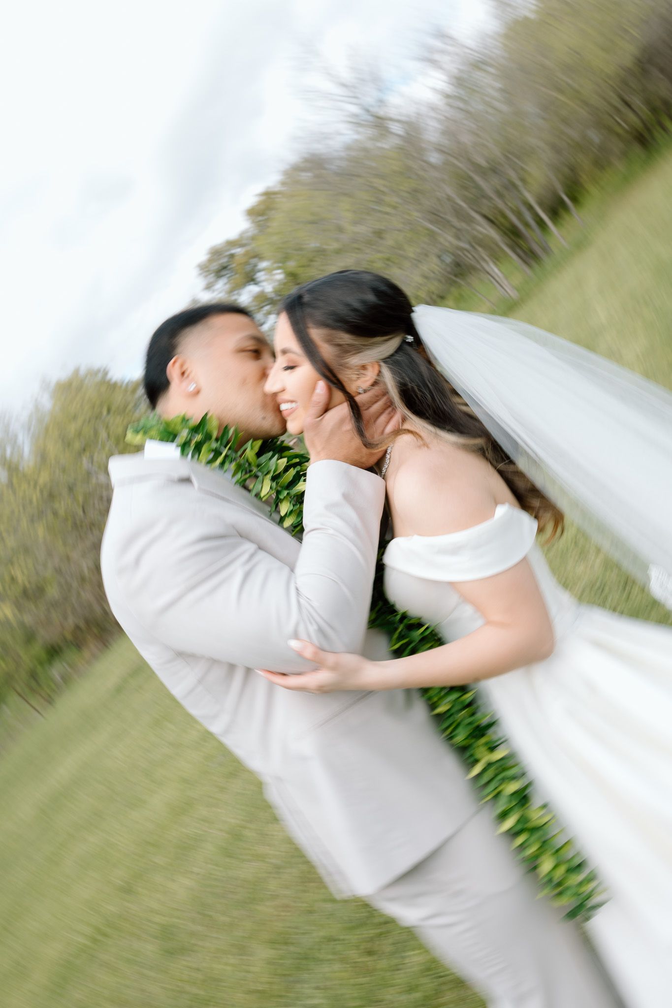 A romantic wedding moment captured in a tilted perspective on grassy grounds.