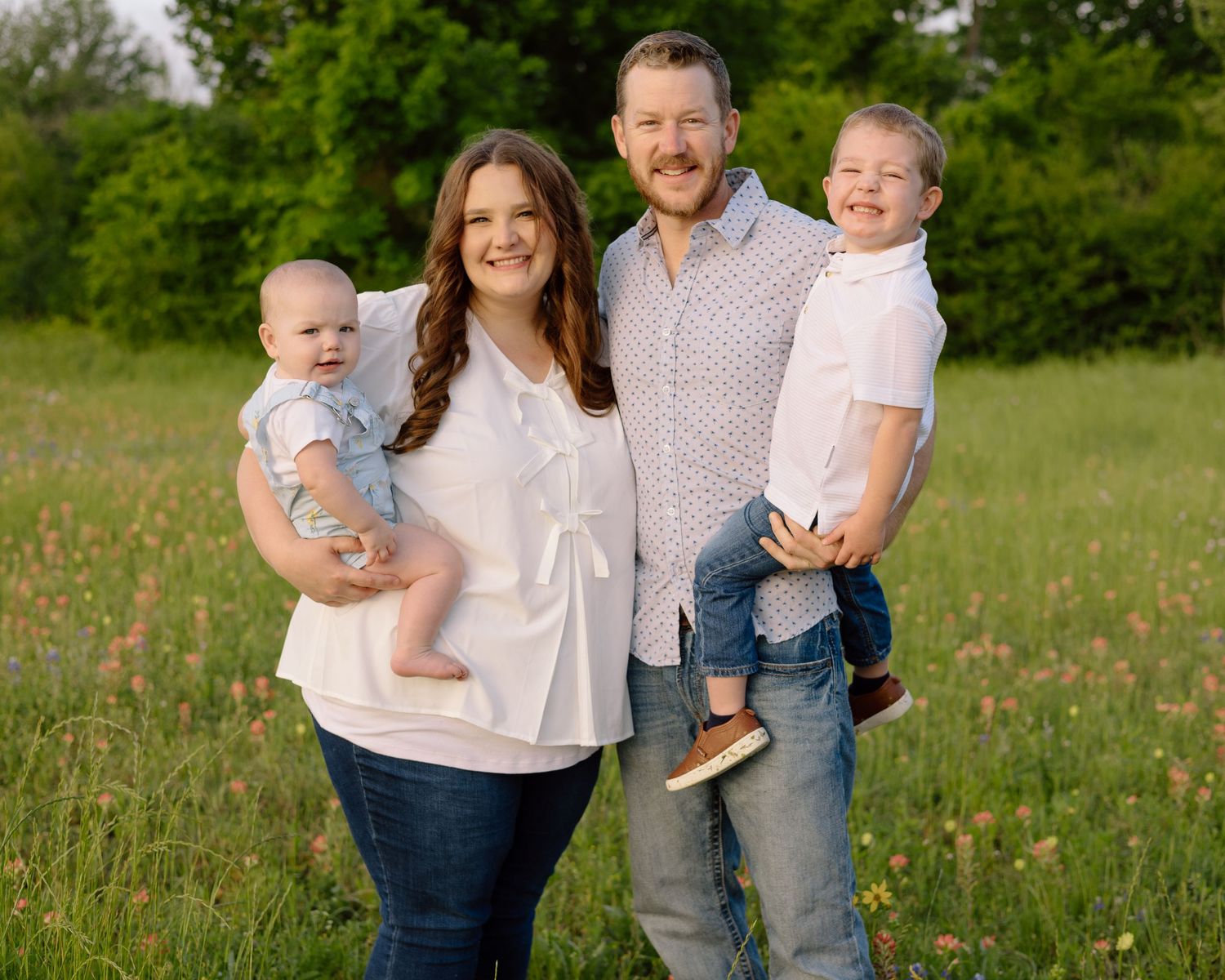 A family poses together in a wildflower field during a summer portrait session.