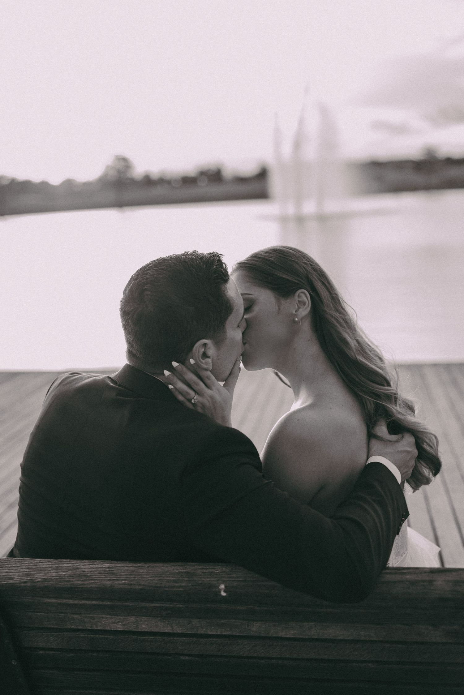 A romantic black and white photo captures an intimate moment between a couple by the water.
