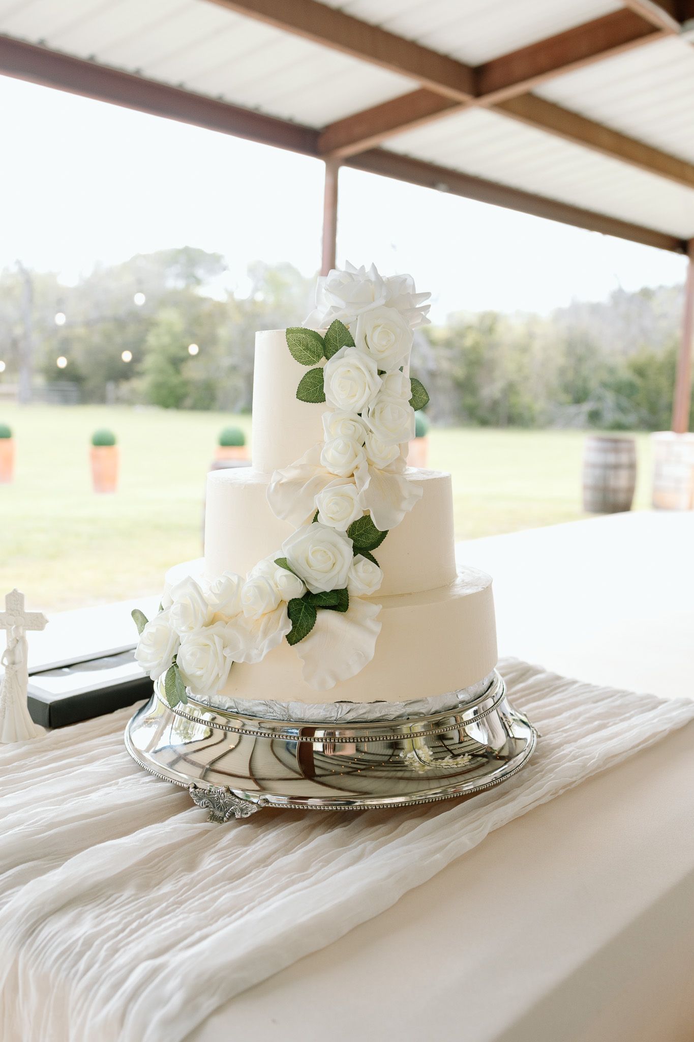 Elegant white tiered wedding cake decorated with fresh flowers displayed on a silver stand.