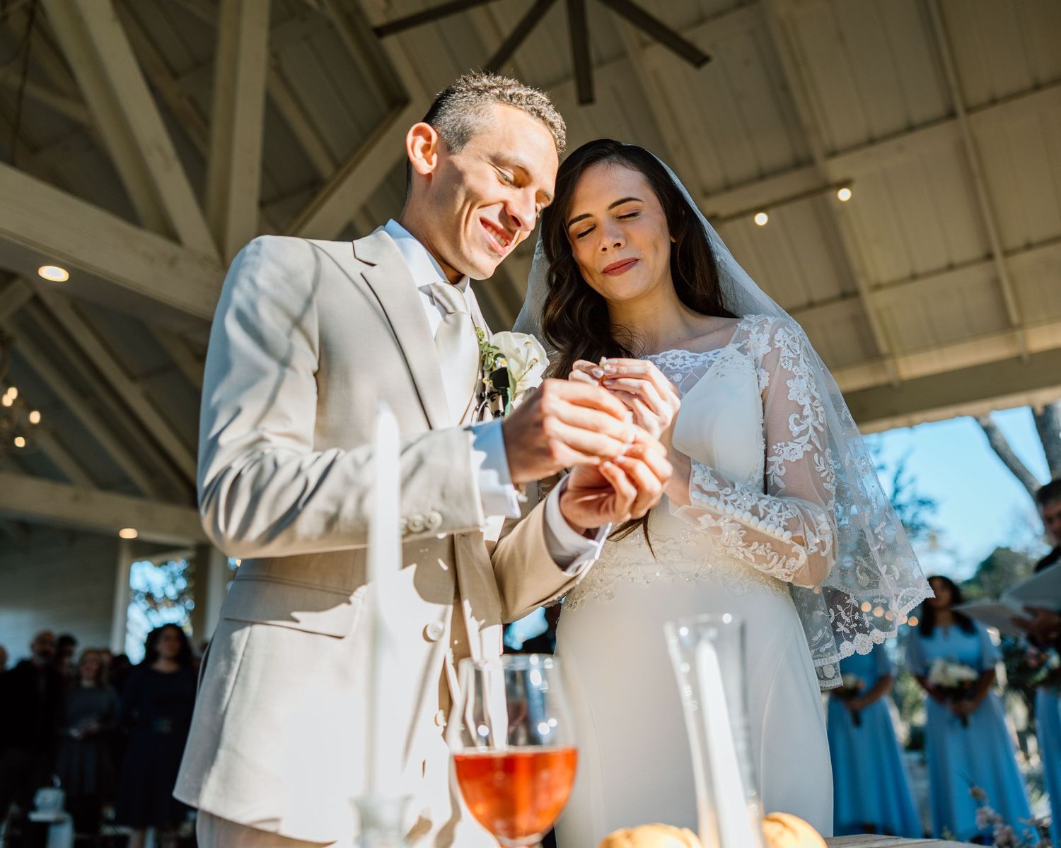 Newlyweds holding hands during unity candle lighting at elegant wedding reception.
