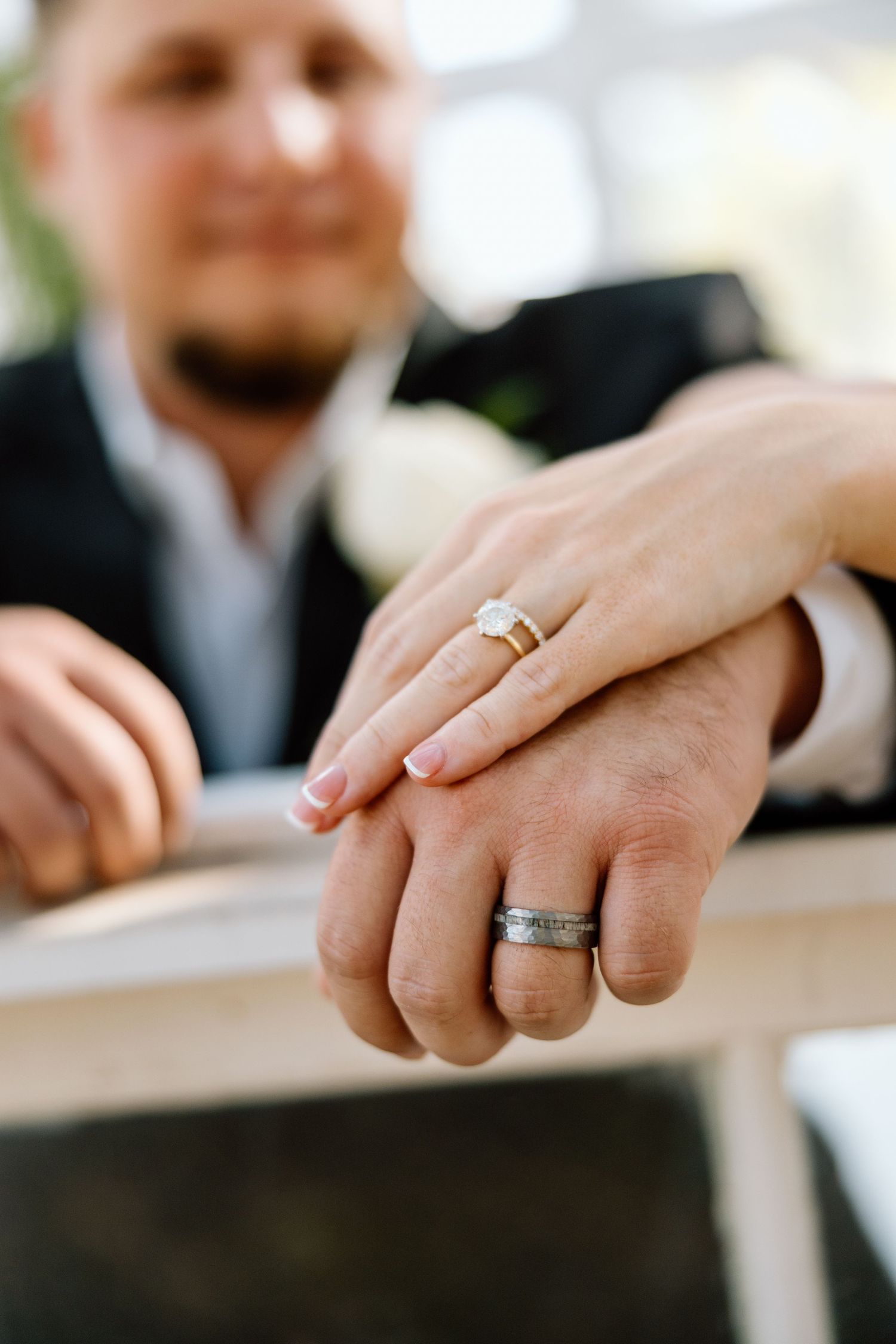 Close-up of newlyweds hands showing diamond engagement ring and silver wedding band after ceremony.