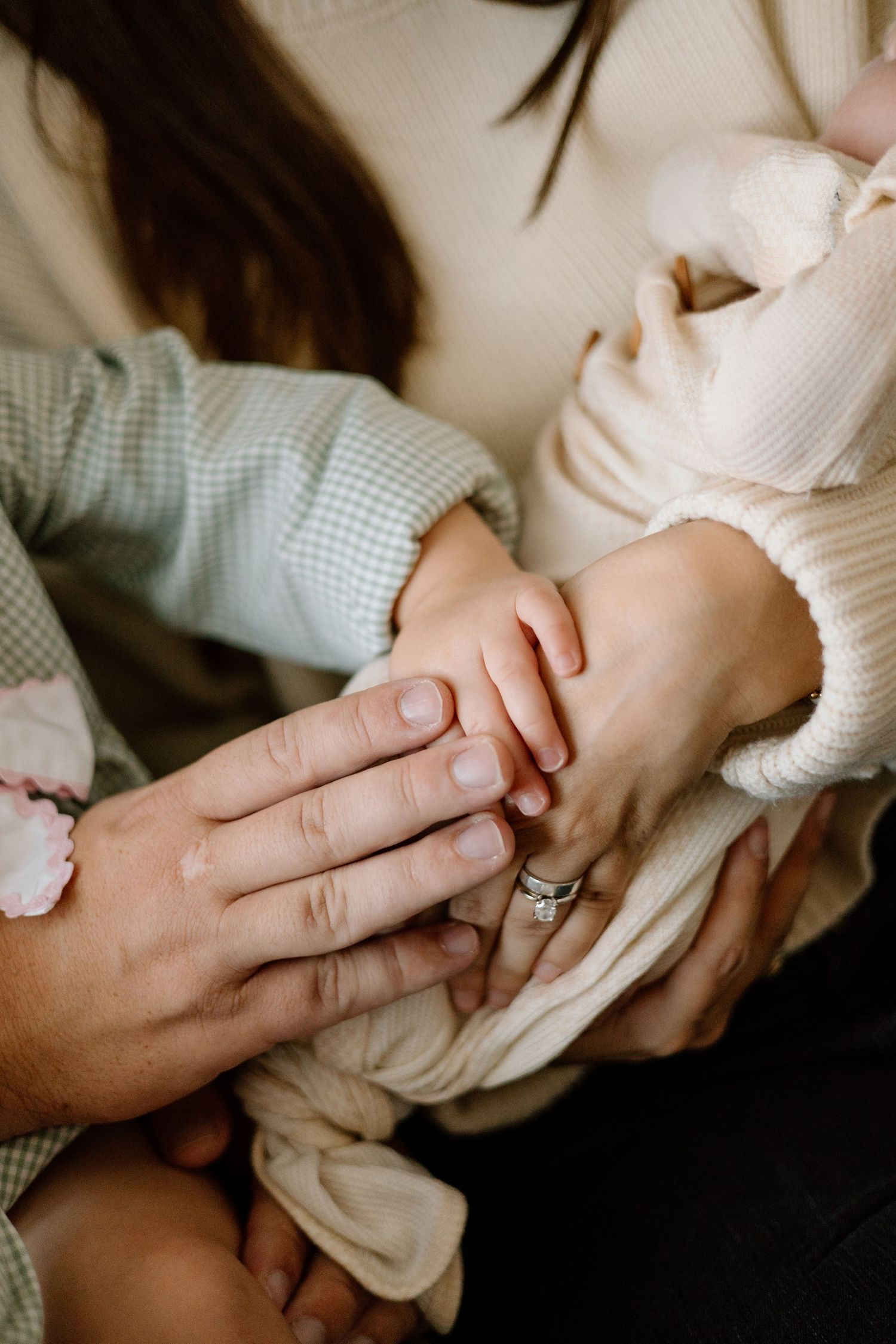 Close-up of a newborn baby's tiny hand resting on parents' hands, symbolizing family love and new life.
