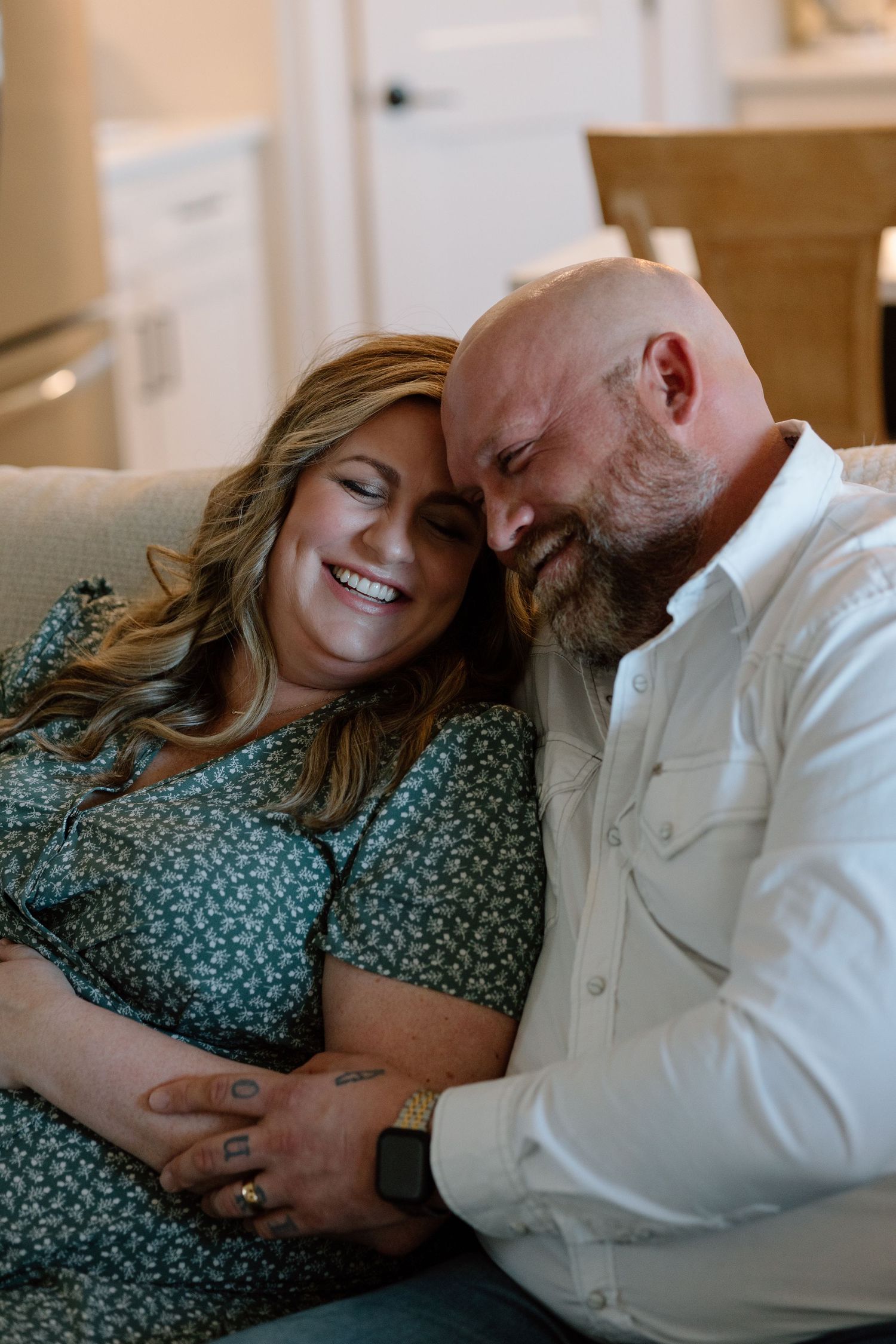 Intimate moment shared between a couple on couch while looking at ultrasound photos.
