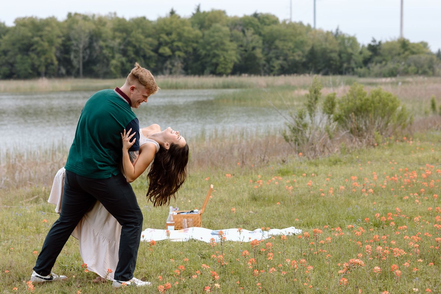 A romantic dip pose between a couple near wildflowers by the lake.